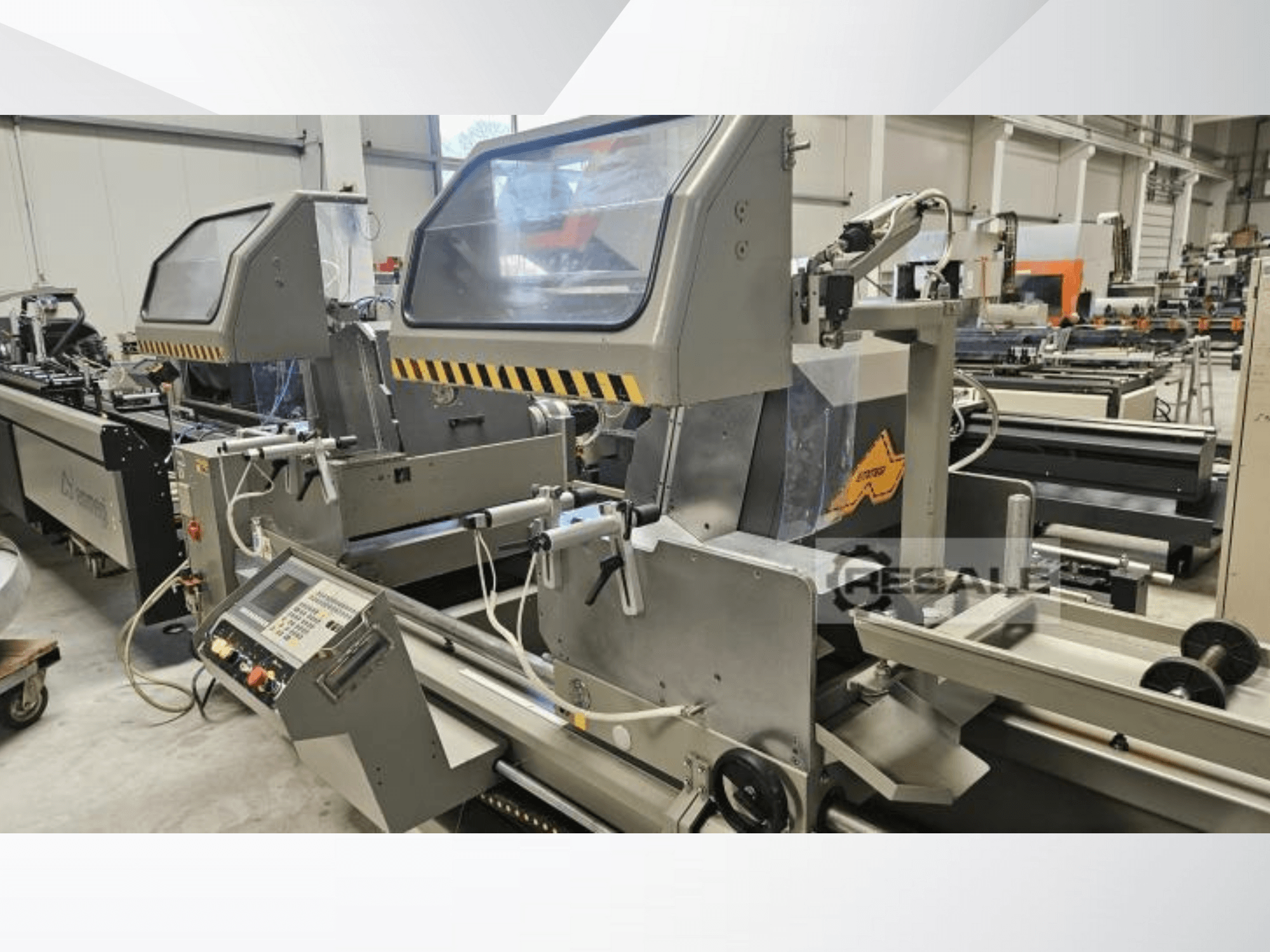 Kaksiksaagimismasinad tehases; esiplaanil on näidatud juhtpaneel, klaaskatted ja lõikekomponendid.