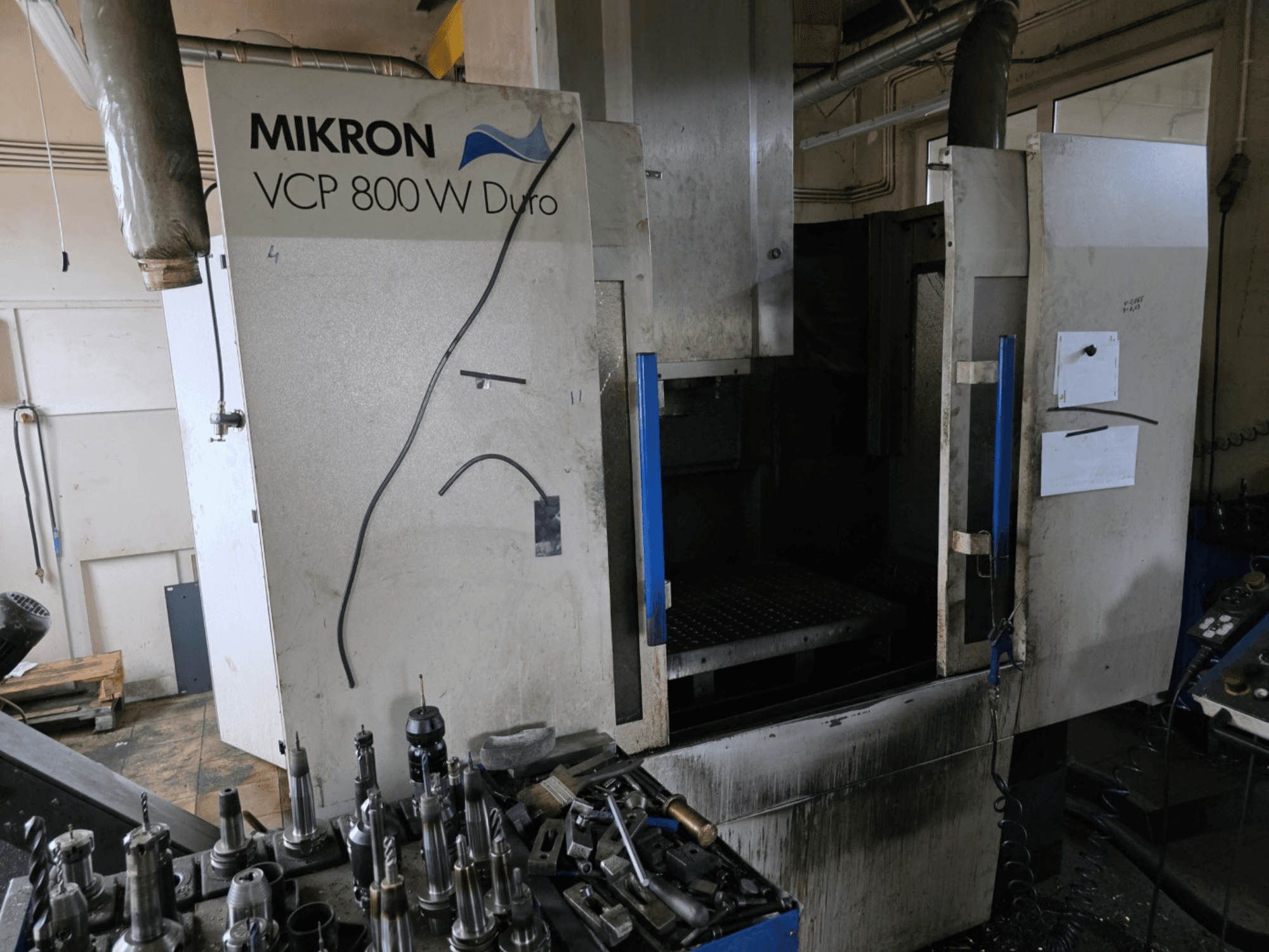 Mikron VCP 800 W Duro freespingi külgvaates, esiplaanil tööriistad ja juhtimisseadmed.