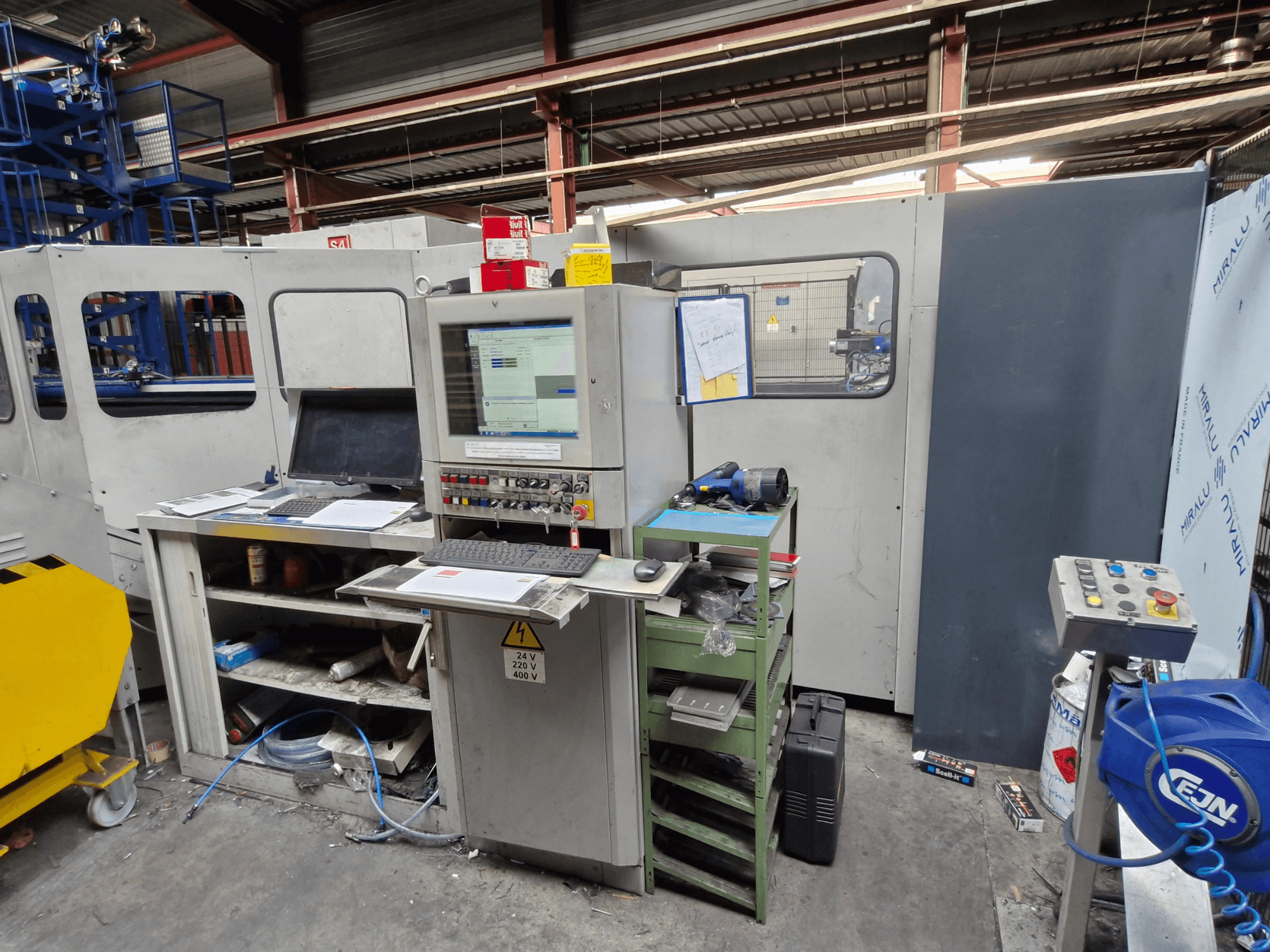 CNC stantsimismasin Salvagnini S4-40 töökojas, kus on juhtpaneel koos monitoride ja tööriistadega, esiplaanil.