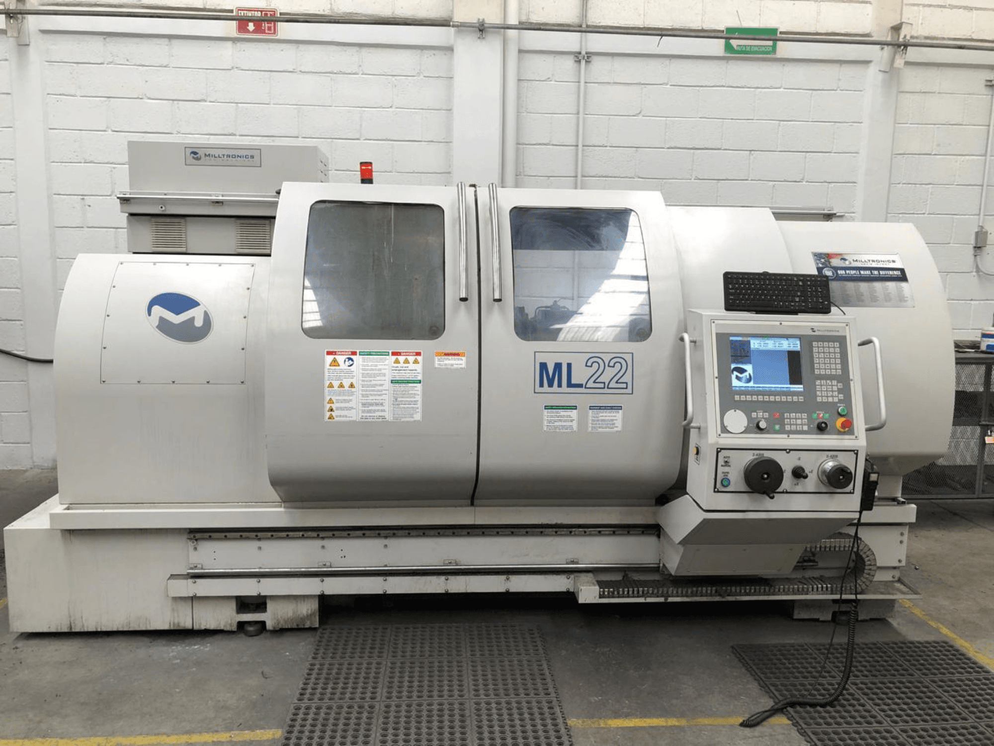Vertikaalne töötlemiskeskus MILLTRONICS RH 20, esiplaanil on juhtpaneel, kaubamärgi logo ja ohutusmärgised masinal.