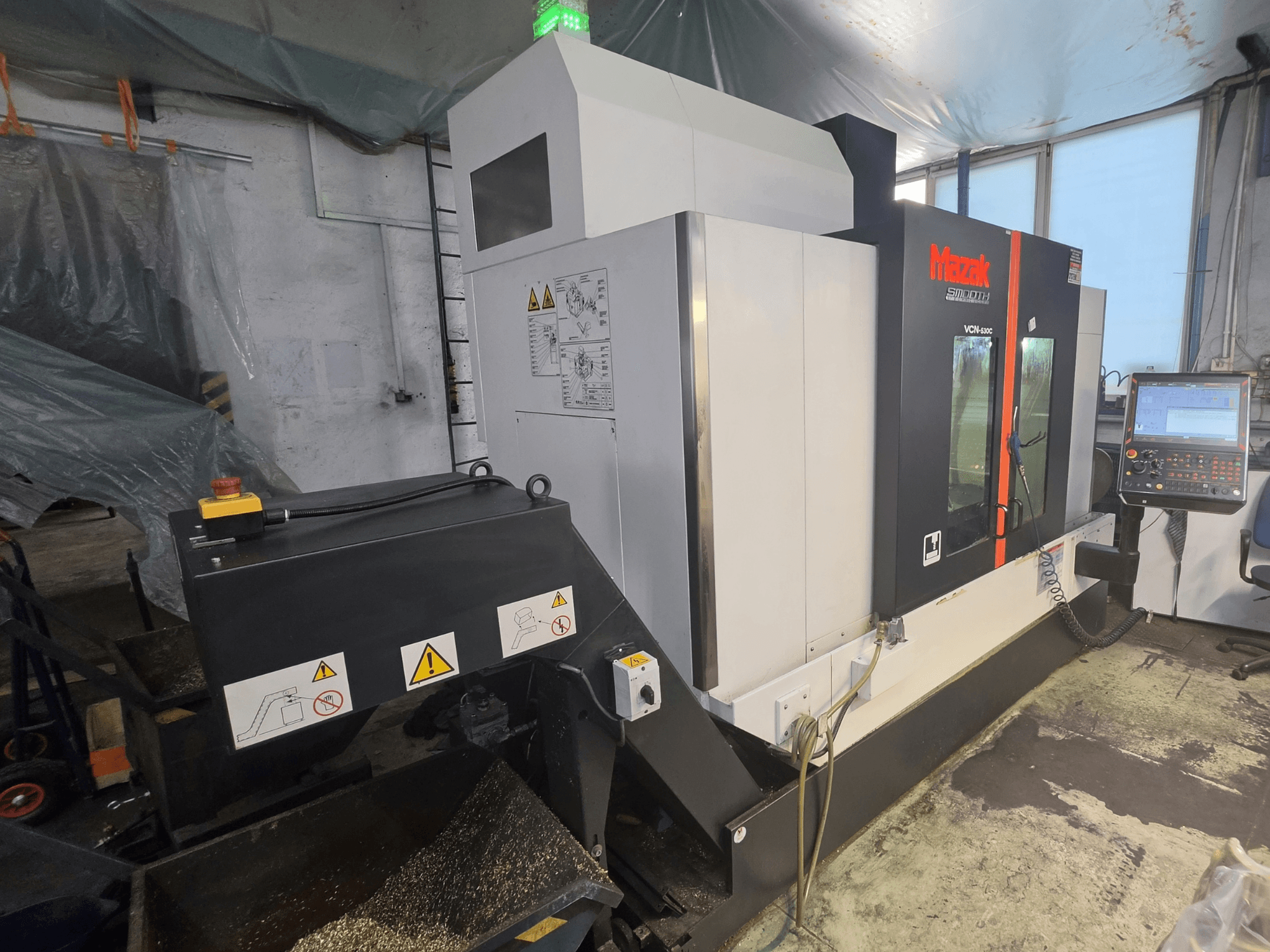 Mazak VCN-530C vertikaalse töötlemiskeskuse esivaade, millel on näha juhtpaneel, tööriistade ahel ja töötamisnäidikud.