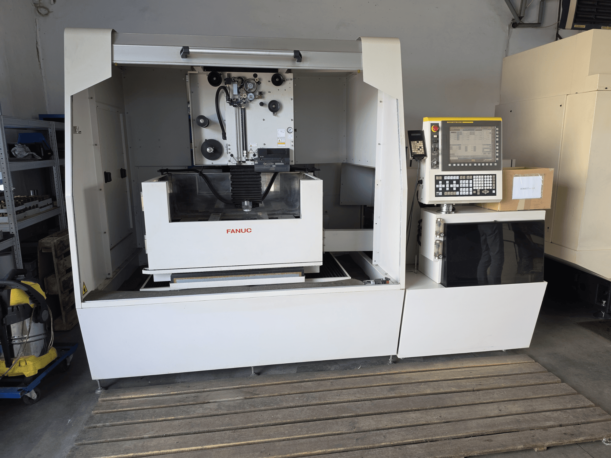 FANUC ROBOCUT alpha-1iD traat-EDM-masin, esivaade, millel on näha juhtpaneel, tööala ja kompaktne disain töökoda keskkonnas.