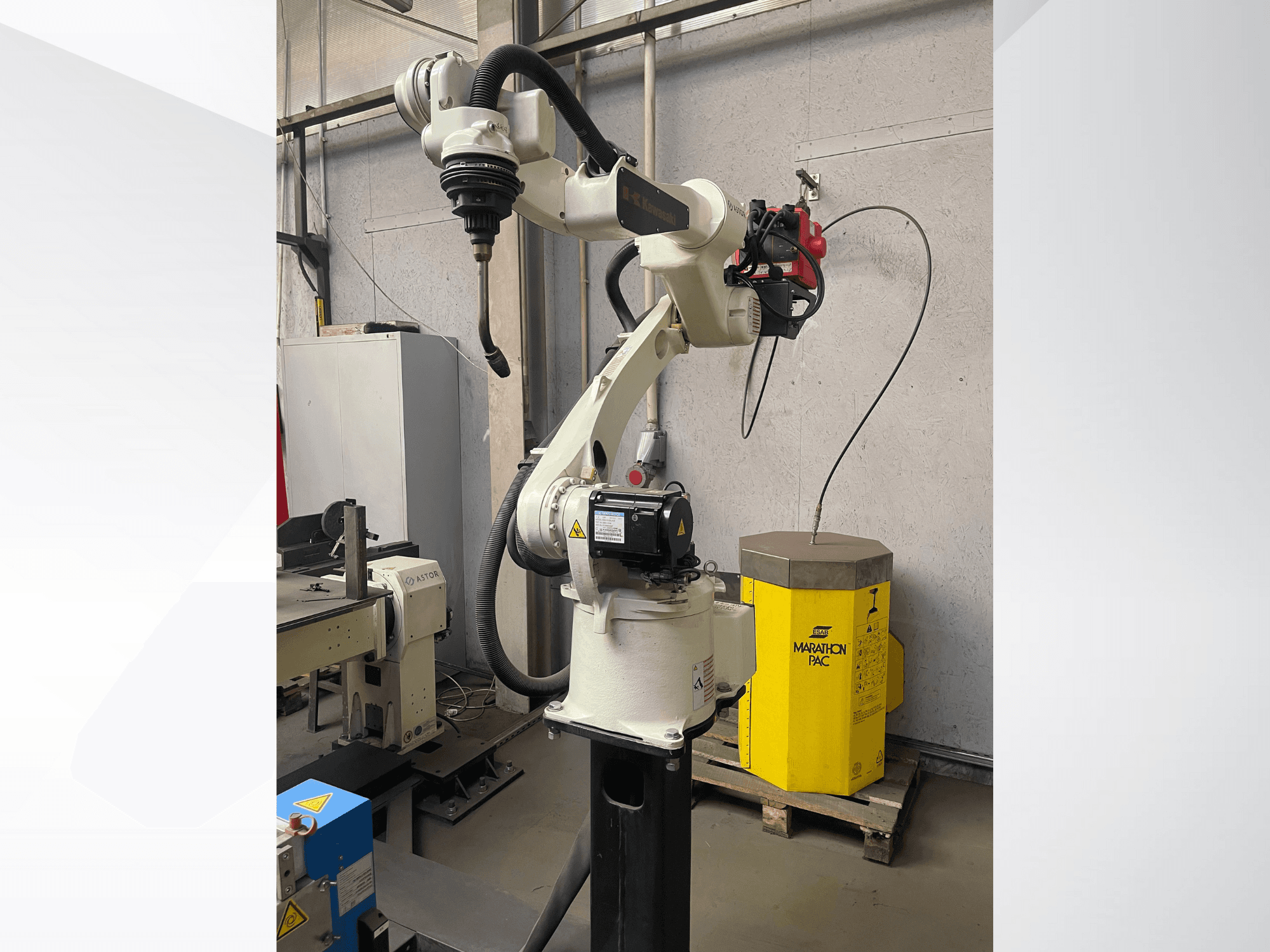 Kawasaki robotkäsi külgvaates, millel on paigaldatud tööriistahoidik, taustal kollane jõuseade.