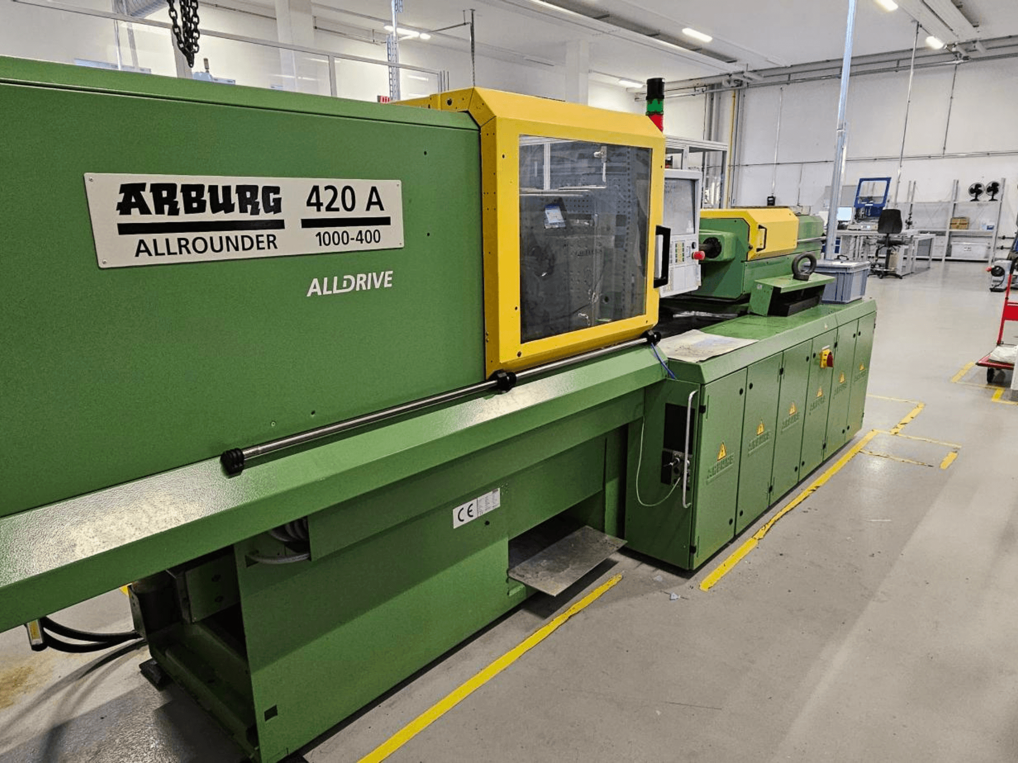 ARBURG 420 A Allrounder 1000-400, esivaade; roheline masin kollase paneeli, puuteekraani ja turvaelementidega.