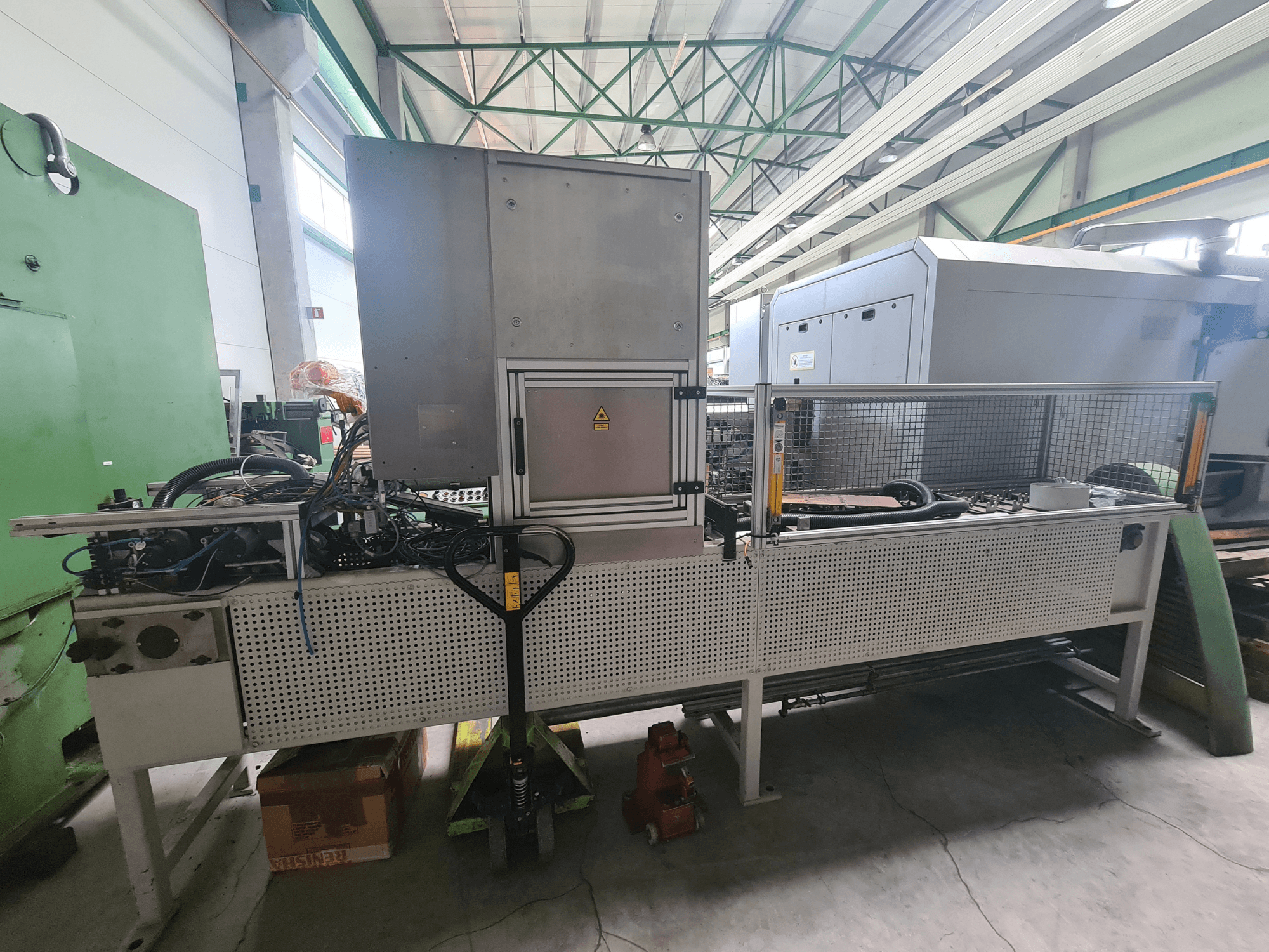 Metallraami, voolikute ja juhtpaneeliga tööstusmasinad, tehases küljelt vaadatuna.