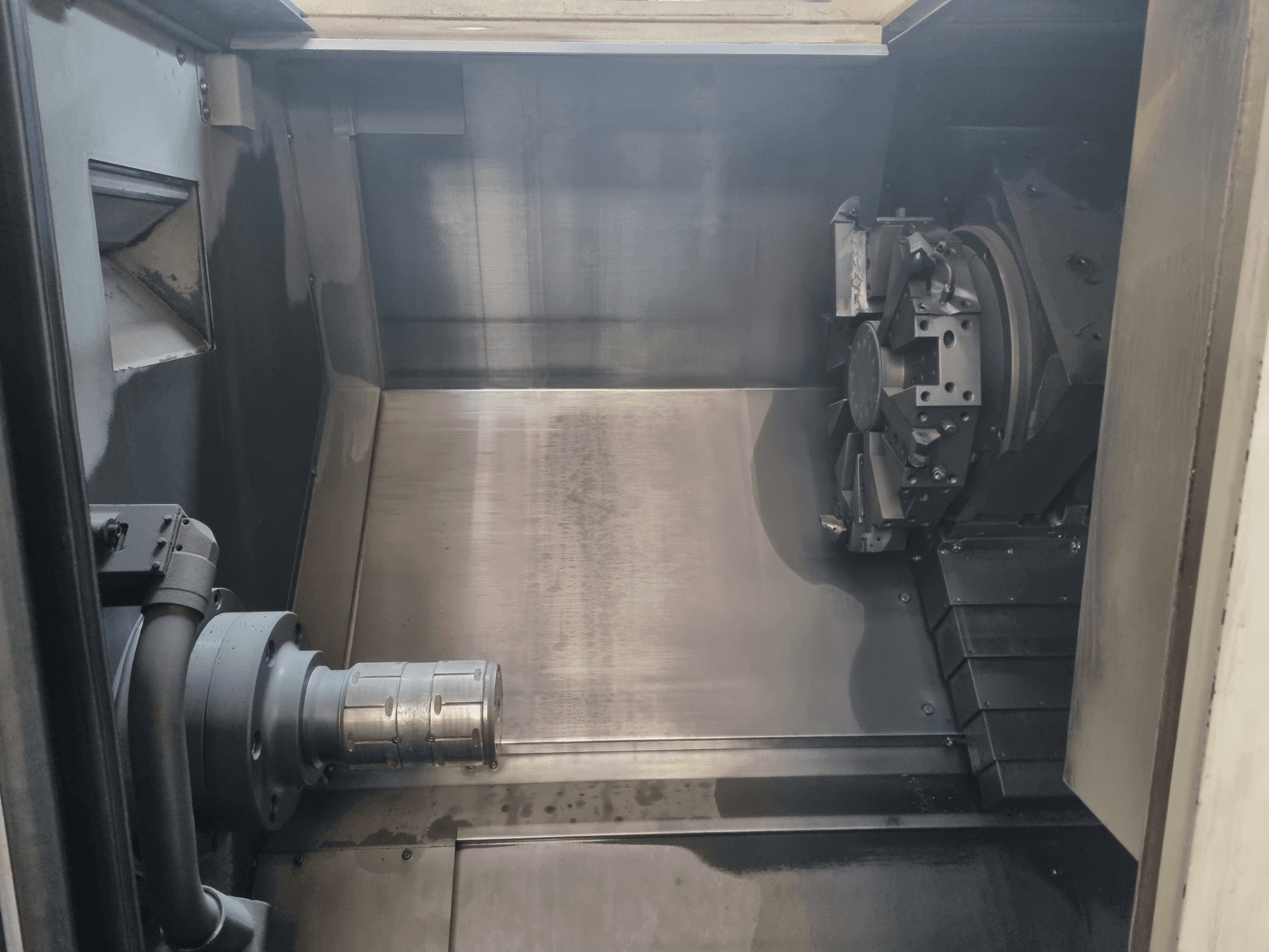 CNC-pingi sisevaade, millel on kujutatud metalltööpiirkond, tööriistahoidja ja toorik; rõhutab täppistehnoloogiat.