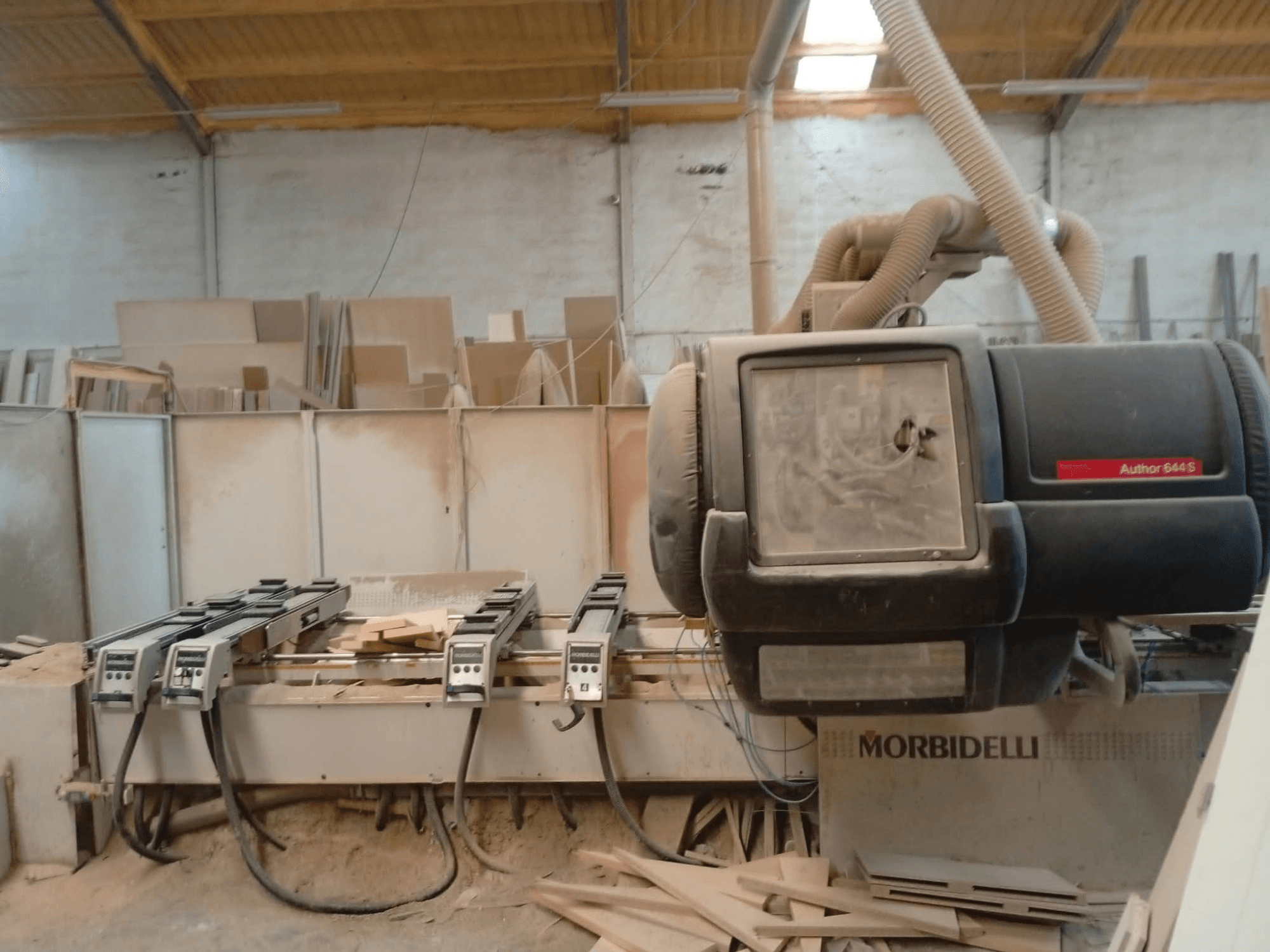 Töökojas eksponeeritud CNC-töötluskeskus MORBIDELLI A644S FTP 41 PC, millel on näha esivaade koos tolmu ja puidujäätmetega.