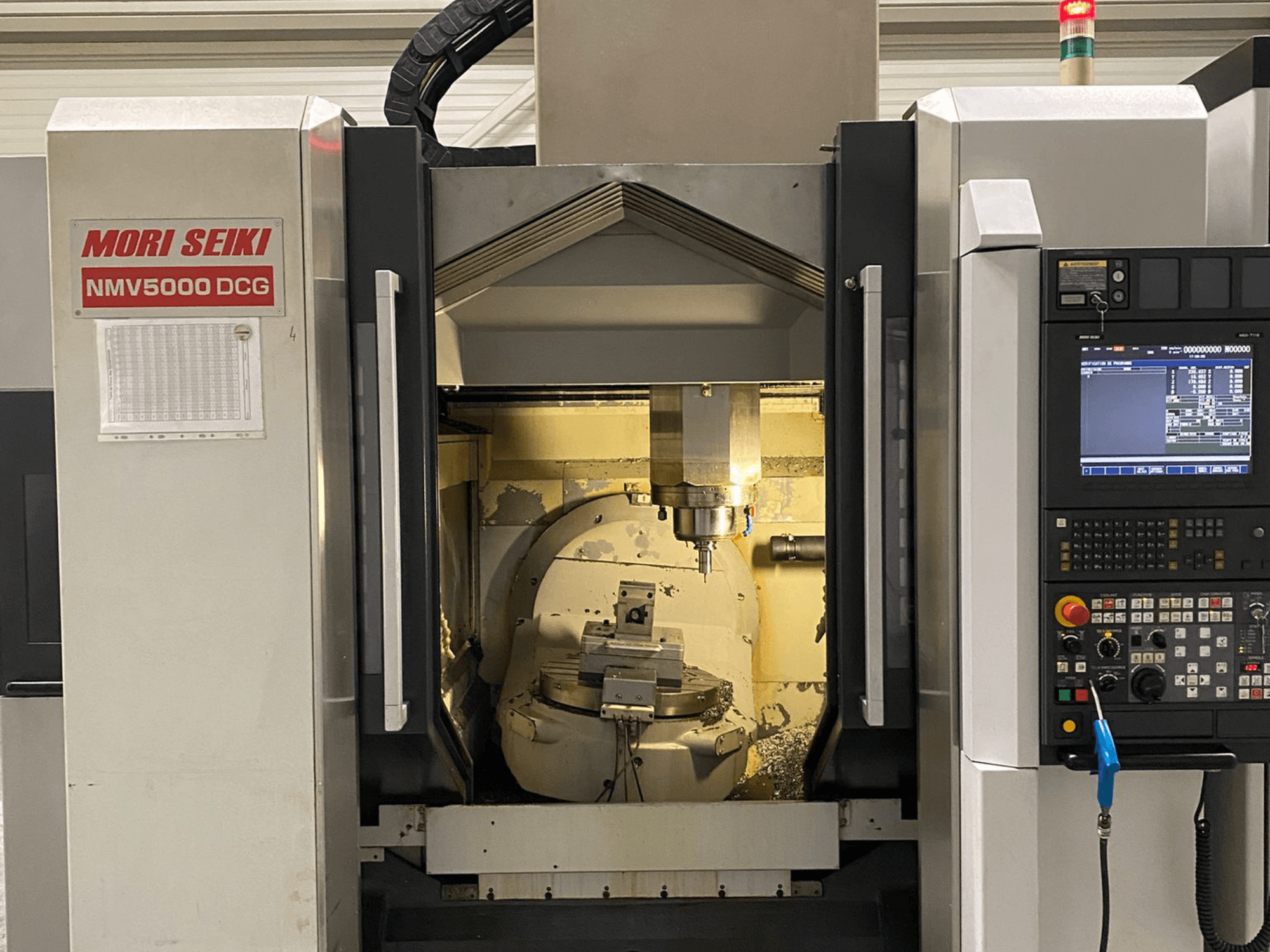 MORI SEIKI NMV 5000DCG universaalne töötlemiskeskus, esiplaanil on juhtpaneel ja sisemine töötlemisala.