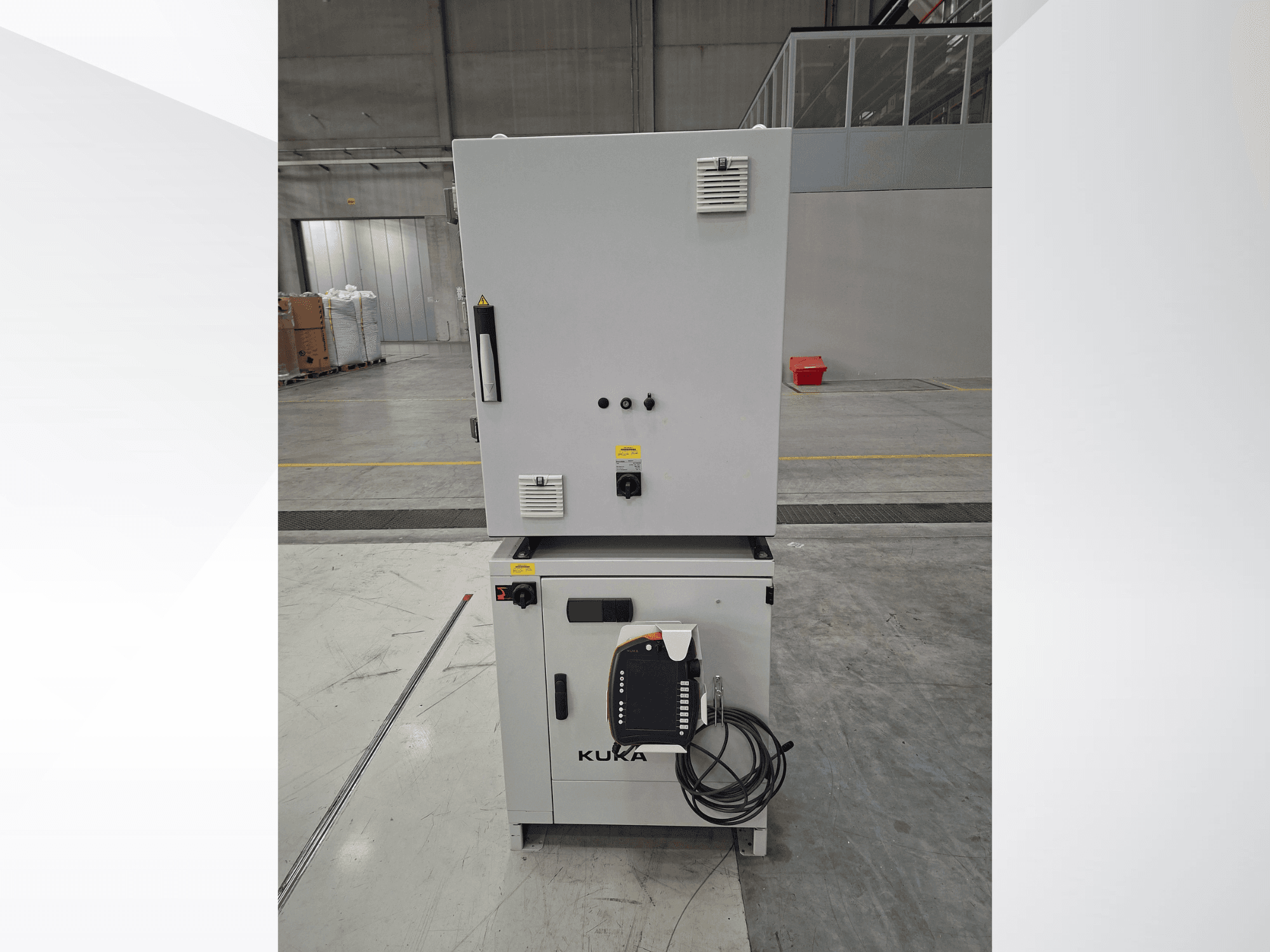 KUKA KR 90 R2700 PRO C4 FLR robotkäe juhtseade, esivaade, millel on näha juhtpaneel ja ohutusmärgised avaras laos.