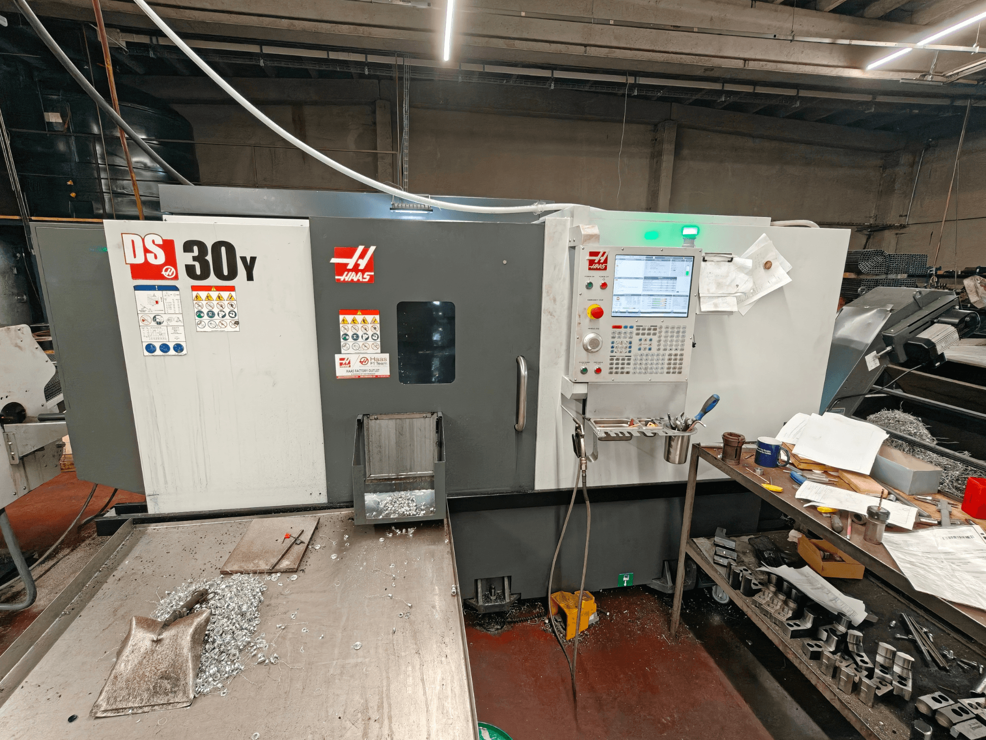 Töökojas asuv horisontaalne treipink HAAS DS30Y, esivaade, millel on näha juhtpaneel ja pinnal olevad metallilaastud.