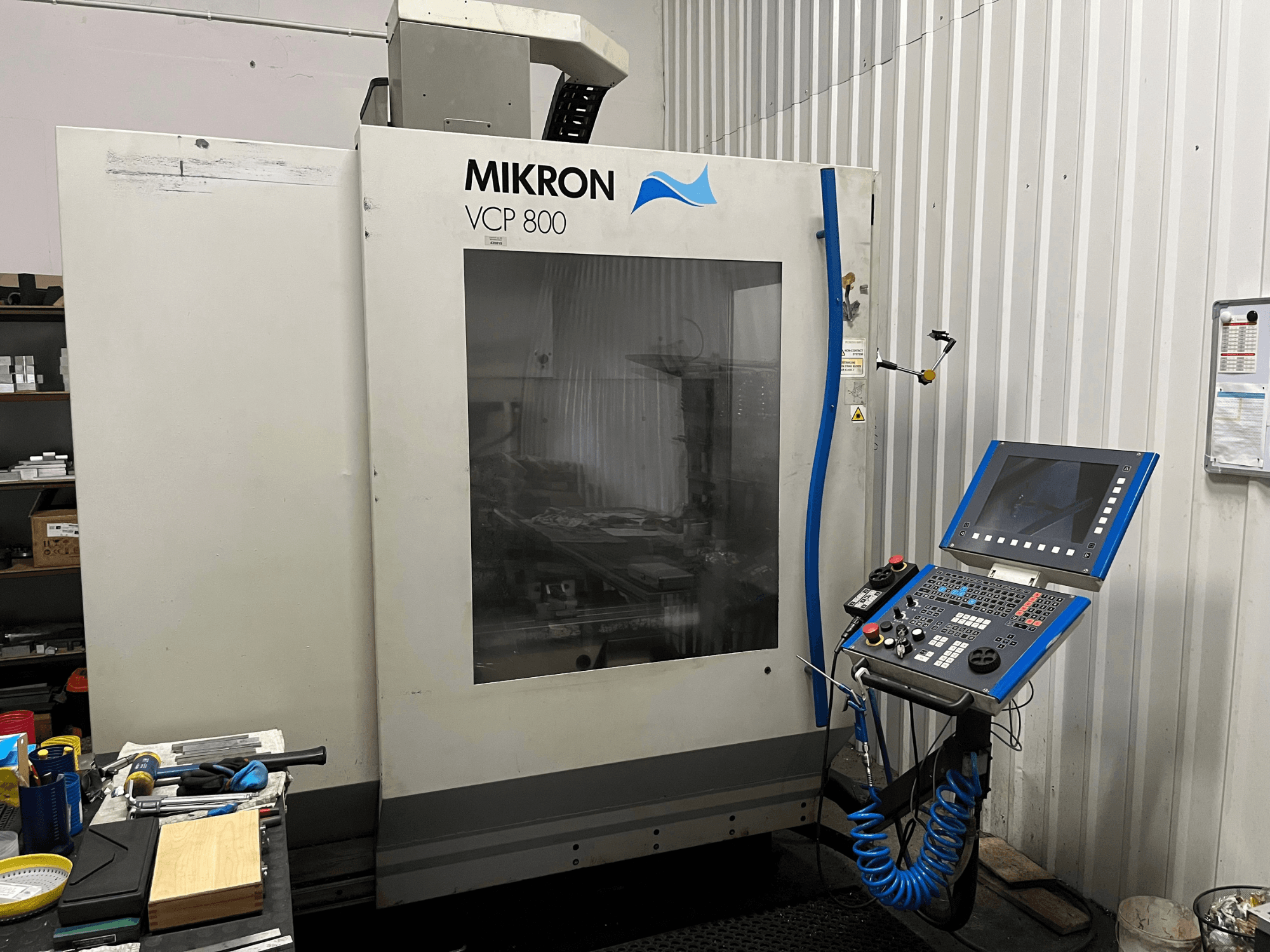 MIKRON VCP 800 vertikaalne töötlemiskeskus, vaade eest, esiplaanil juhtpaneel ja tööpingil olevad tööriistad.