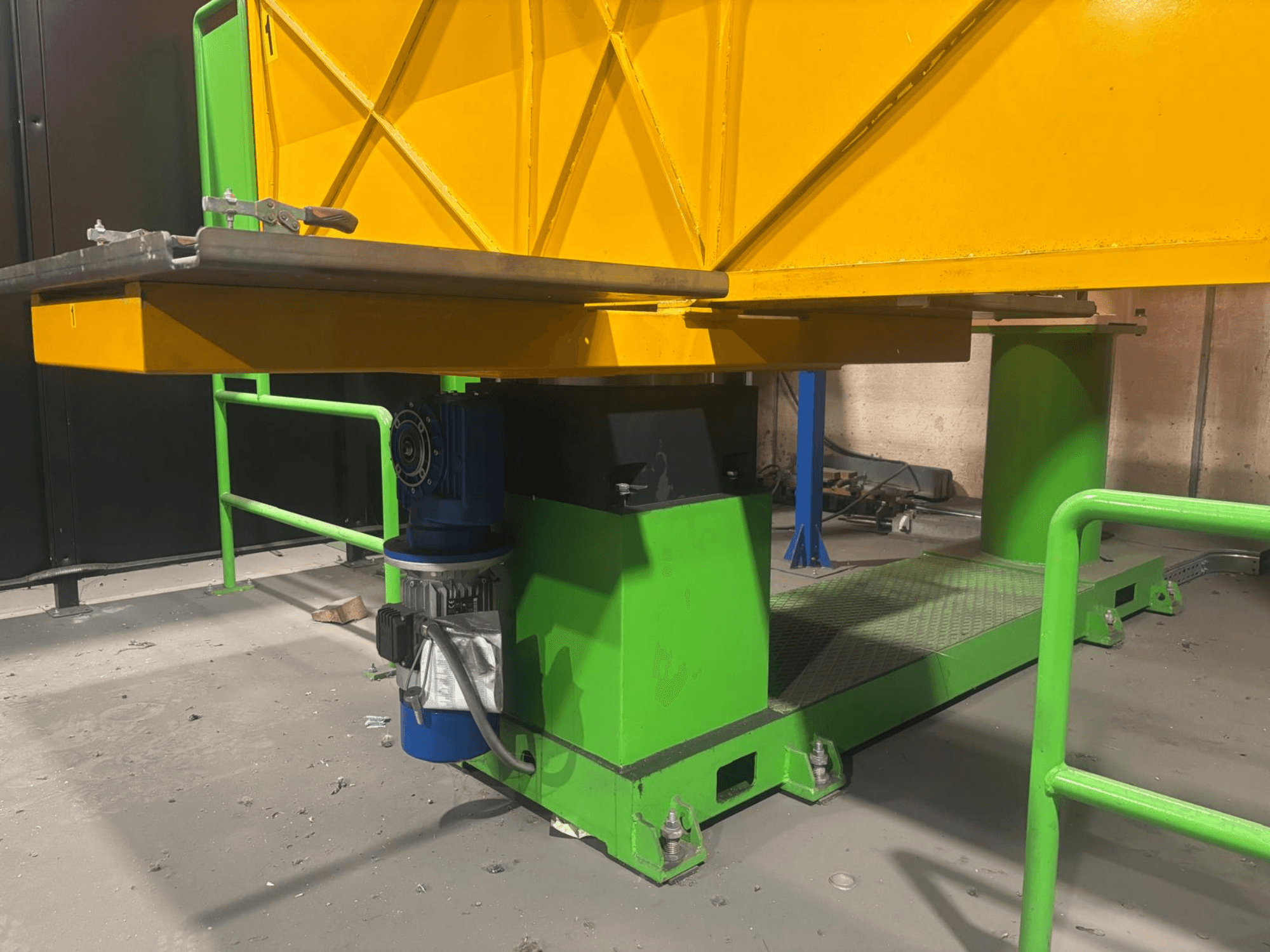 Roheline ja kollane tööstuslik masin madalast esiplaanist, millel on mootor ja tekstuurse pinnaga platvorm.