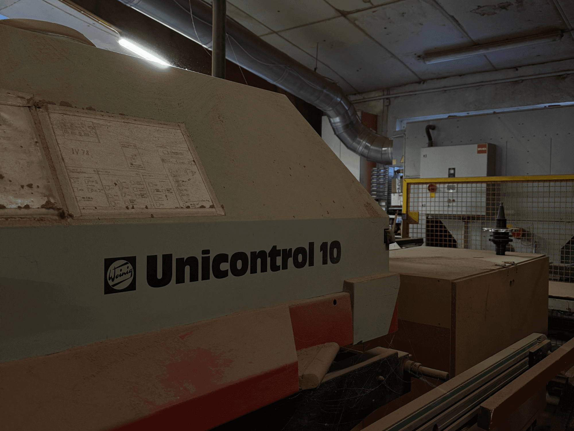 Weinig Unicontrol 10 masin külgnurga alt vaadatuna, tolmune pind, esipaneelil on näha tehnilised skeemid.