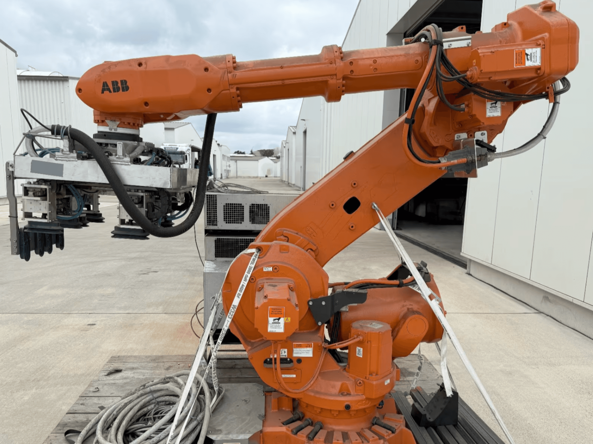 ABB RB 6600-130/3.2 robotkäsi külgvaates, millel on oranž robotkäsi koos haardeseadme kinnitusega ja nähtav juhtmestik.