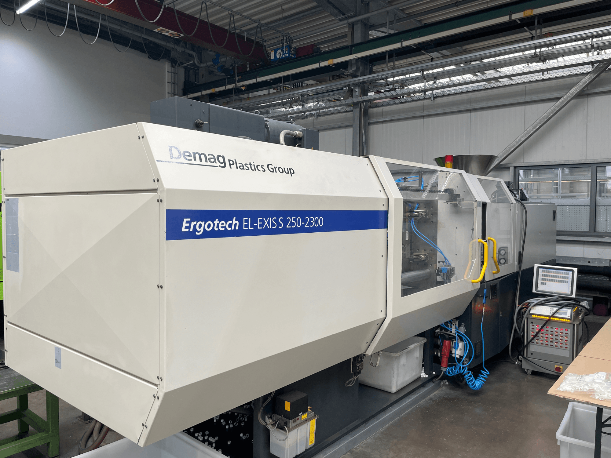 Demag Ergotech EL-EXIS S 250-2300 survevalu masin, külgvaade, kus on näidatud juhtpaneel ja söötmissüsteem.