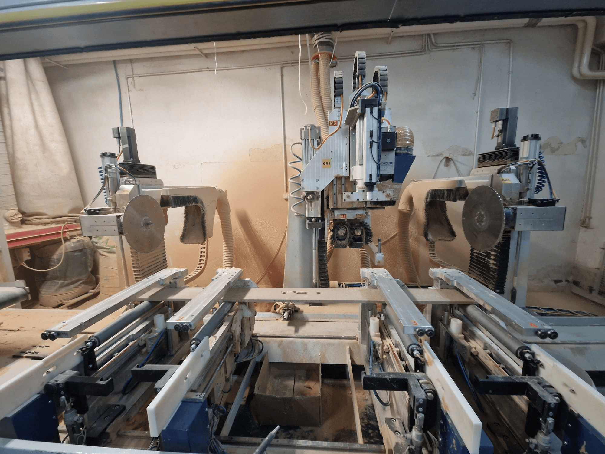 CNC-tööpingi kahe saetera ja rööbastega, esiplaanilt vaadatuna. Nähtav tolmueemaldussüsteem, mis sobib puidutöötlemiseks.