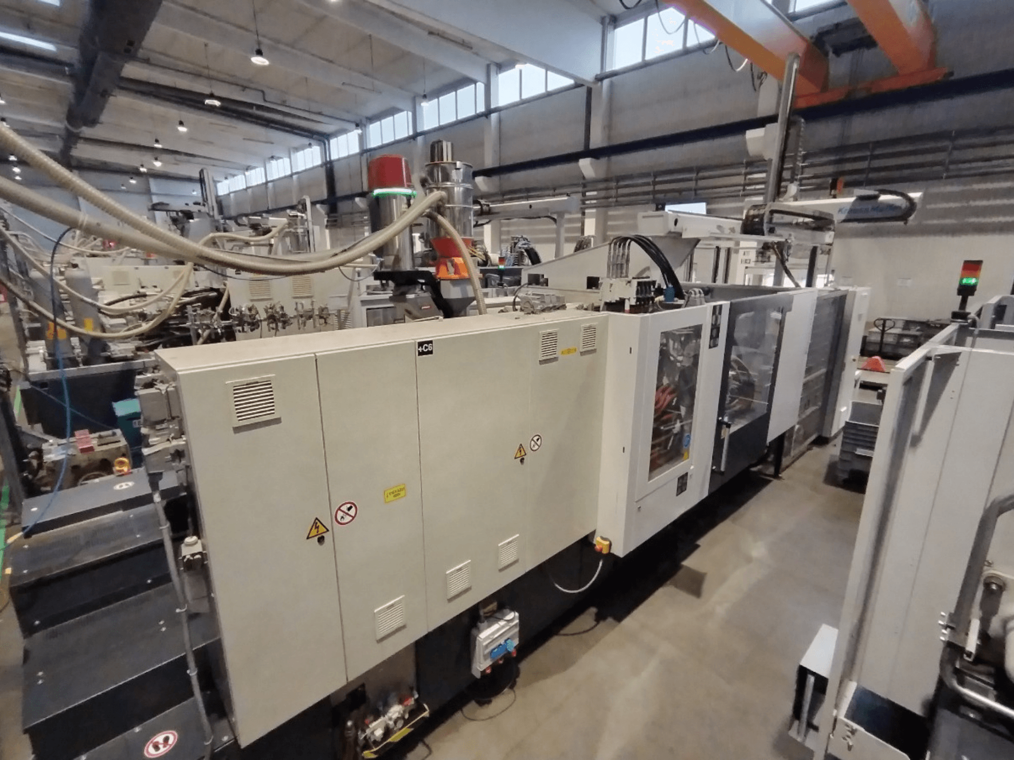 Tööstuslik survevalu masin külgvaates, millel on juhtpaneel ja ohutushoiatused. Kaubamärk: Tundmatu.