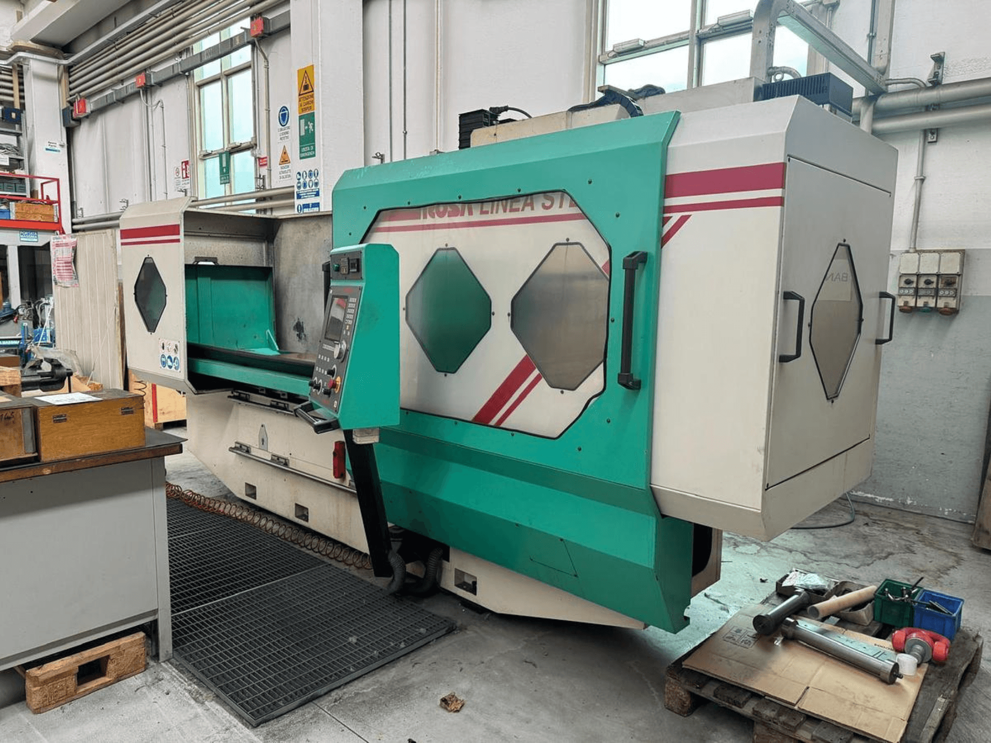 Roheline ja valge täppismasin, esiplaanil, millel on juhtpaneel, tööala ja tööriistad kaubaalusel. Kaubamärk: BAMB.