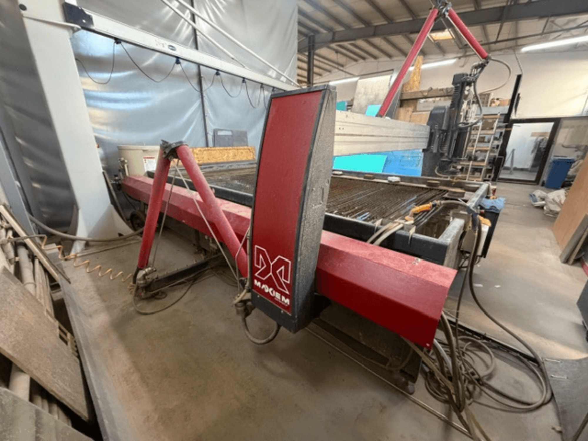 Punane veesüstlilõikamismasin tootemargi X küljelt vaadatuna, millel on näha mehaanilised komponendid ja torustiku üksikasjad.