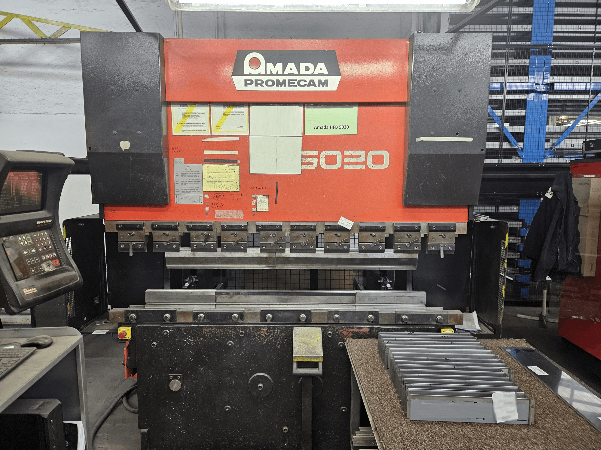 Amada HFBO 5020 presspink eesvaates, kus on juhtpaneel ja metallosad tööpinnal.