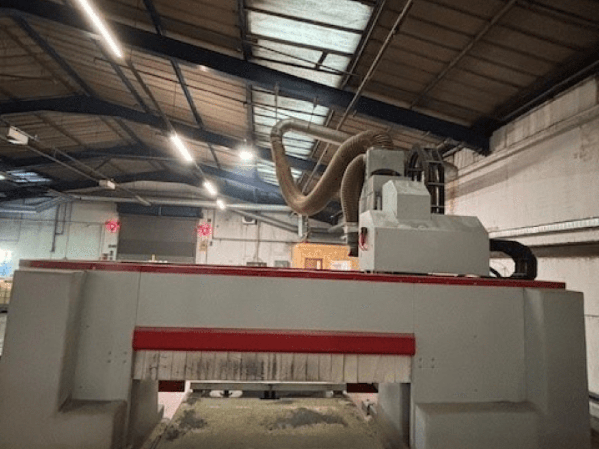 CNC-freesimismasin töökojas, külgvaade, mis rõhutab punast ja halli kujundust, tolmueemaldussüsteem on kinnitatud.