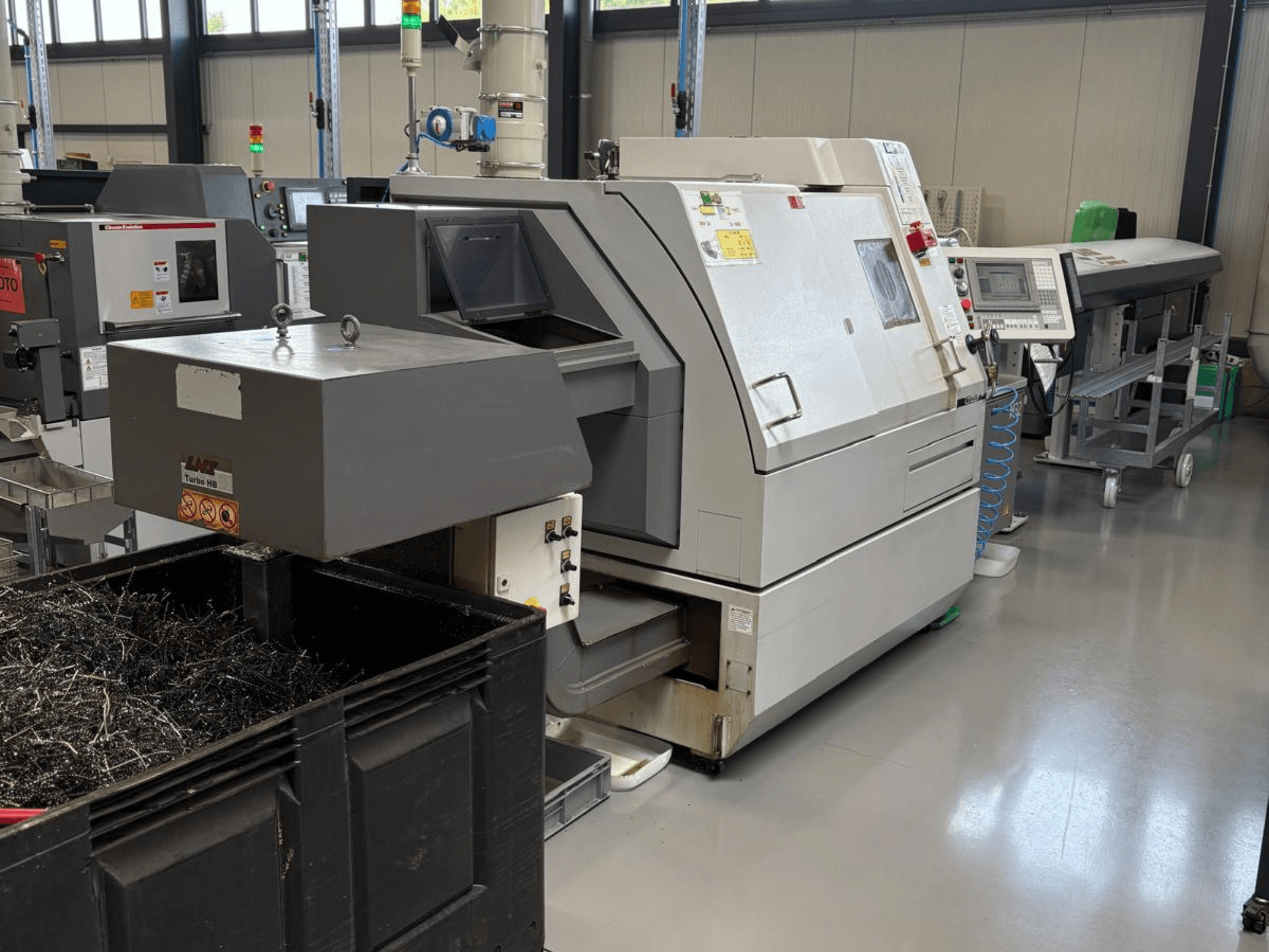 LTA Turbo H8 tööstuslik masin, külgvaade, koos suure metallilaastude konteineri ja juhtpaneeliga tehases.