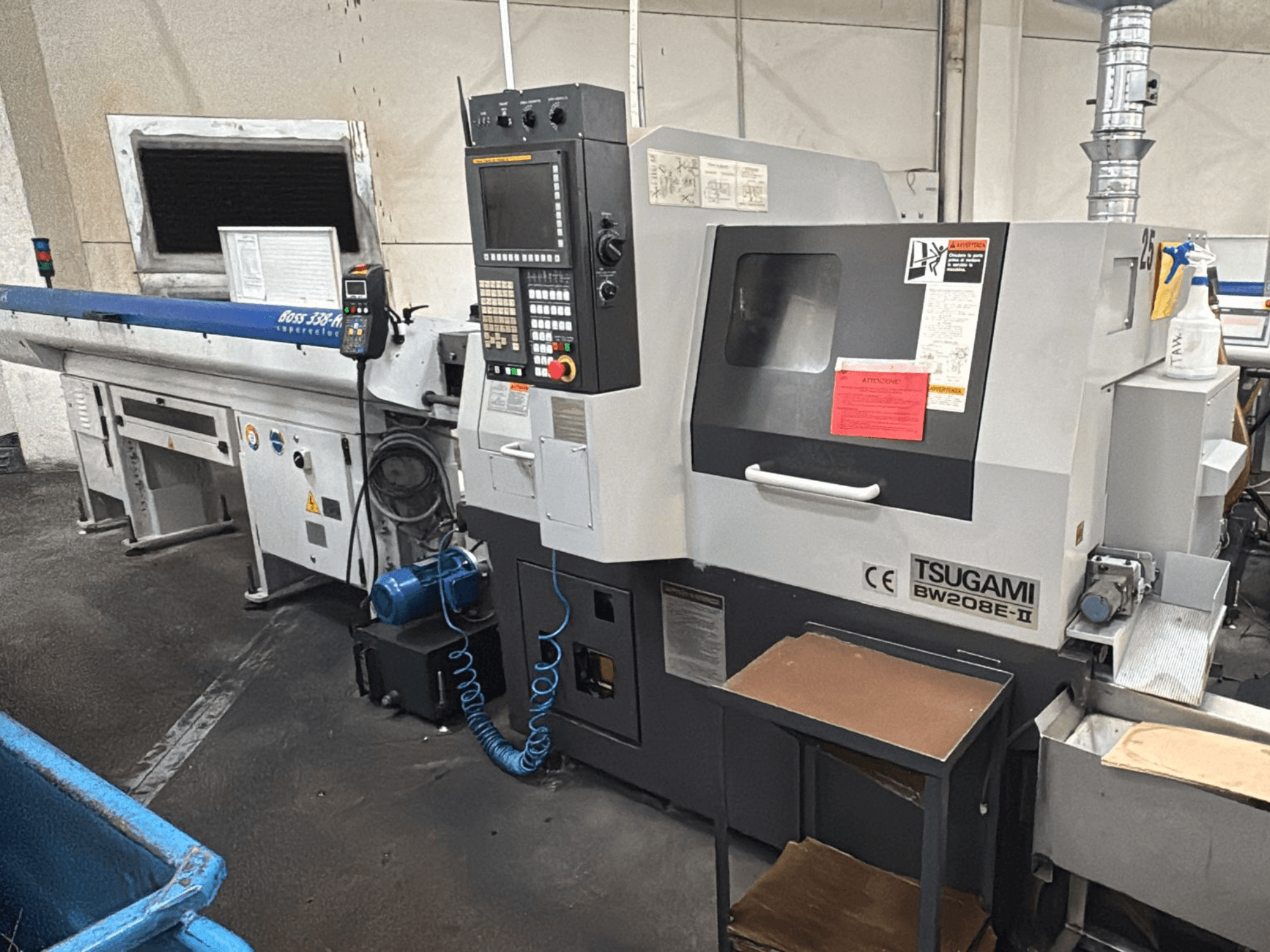 Tsugami BW208E-II CNC-tööpink töökojas, esiplaanilt, juhtpaneel ja ohutussildid nähtavad.