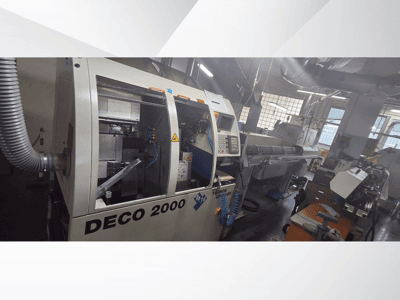 DECO 2000 CNC-tööpink töökojas, esivaade, kus paremal on näidatud juhtimisseadmed ja pikk tööpinkide seadistus.