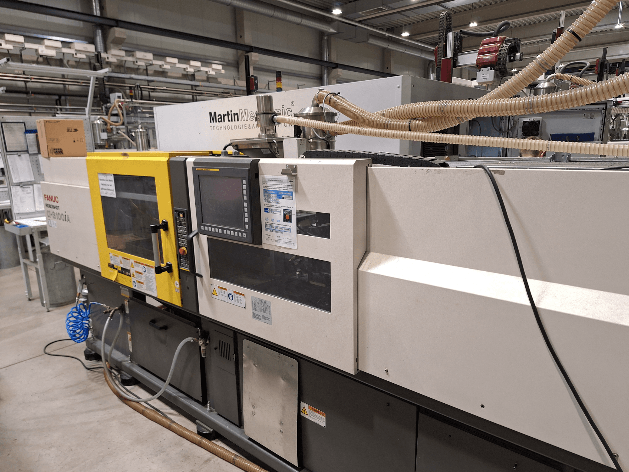 FANUC Roboshot S100iA elektriline survevalu masin, külgvaade, varustatud puuteekraani ja ohutussiltidega.
