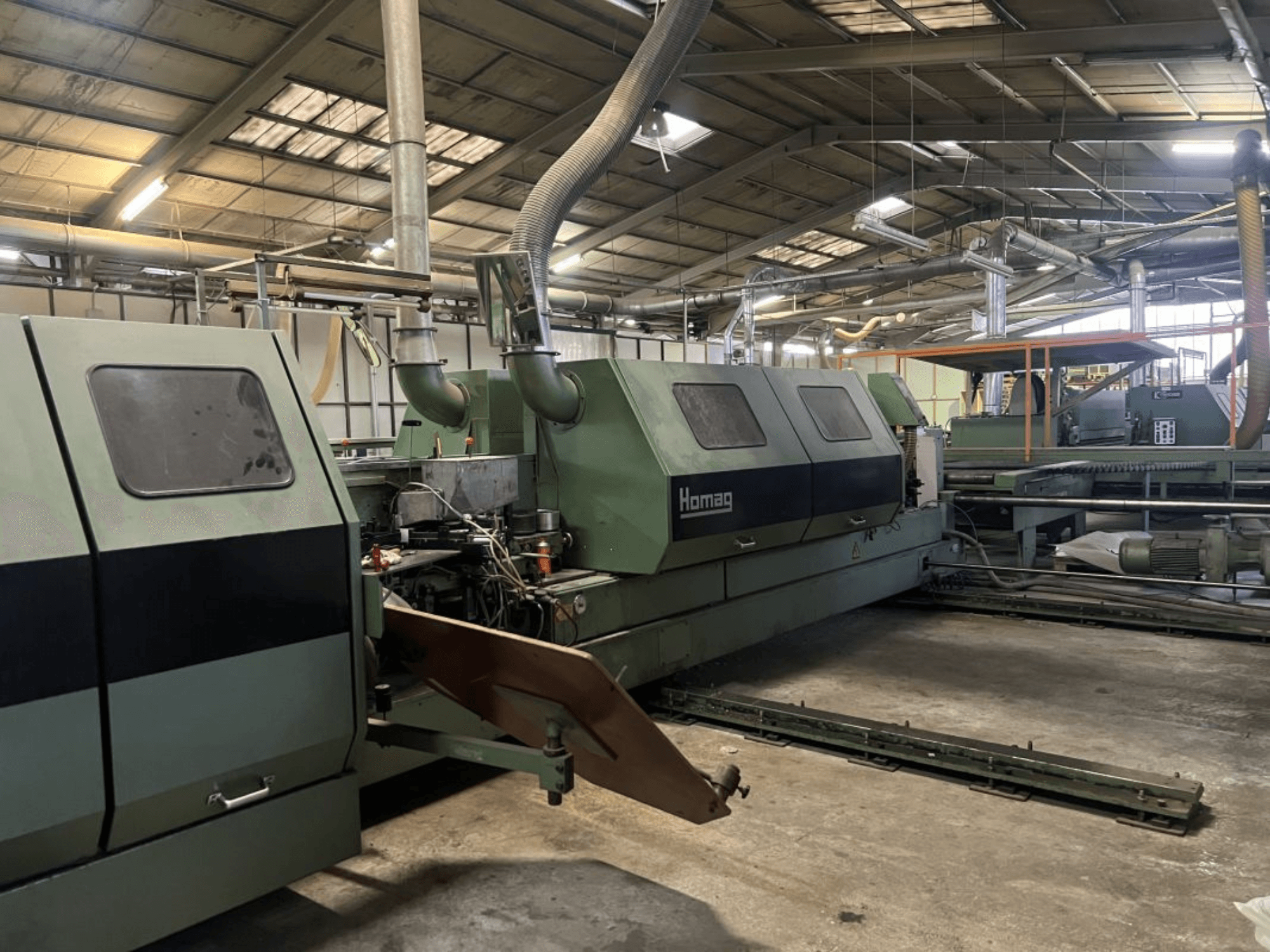 Homagi tööstuslik masin rohelises toonis, külgvaates, töötavate komponentide ja juhtpaneeliga, mis on nähtav laos.