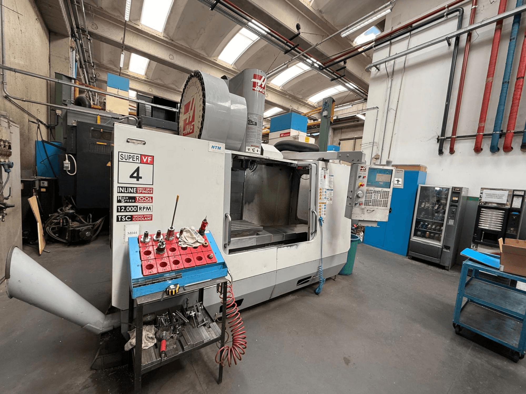 HAAS Super VF 4 CNC-freesping, juhtpaneel, 12 000 pöörlemisspindel ja tööriistad sinisel hoiuraamil, külgvaade.