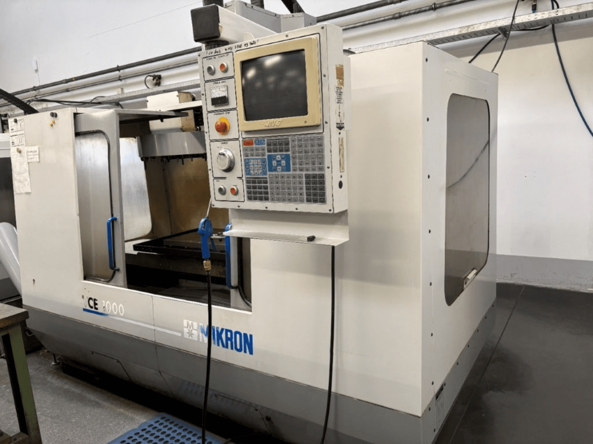 Mikron CE 2000 CNC-tööpink, esiplaan; juhtpaneel koos nuppude ja ekraaniga, hõbedane välisilme ja tööpind.