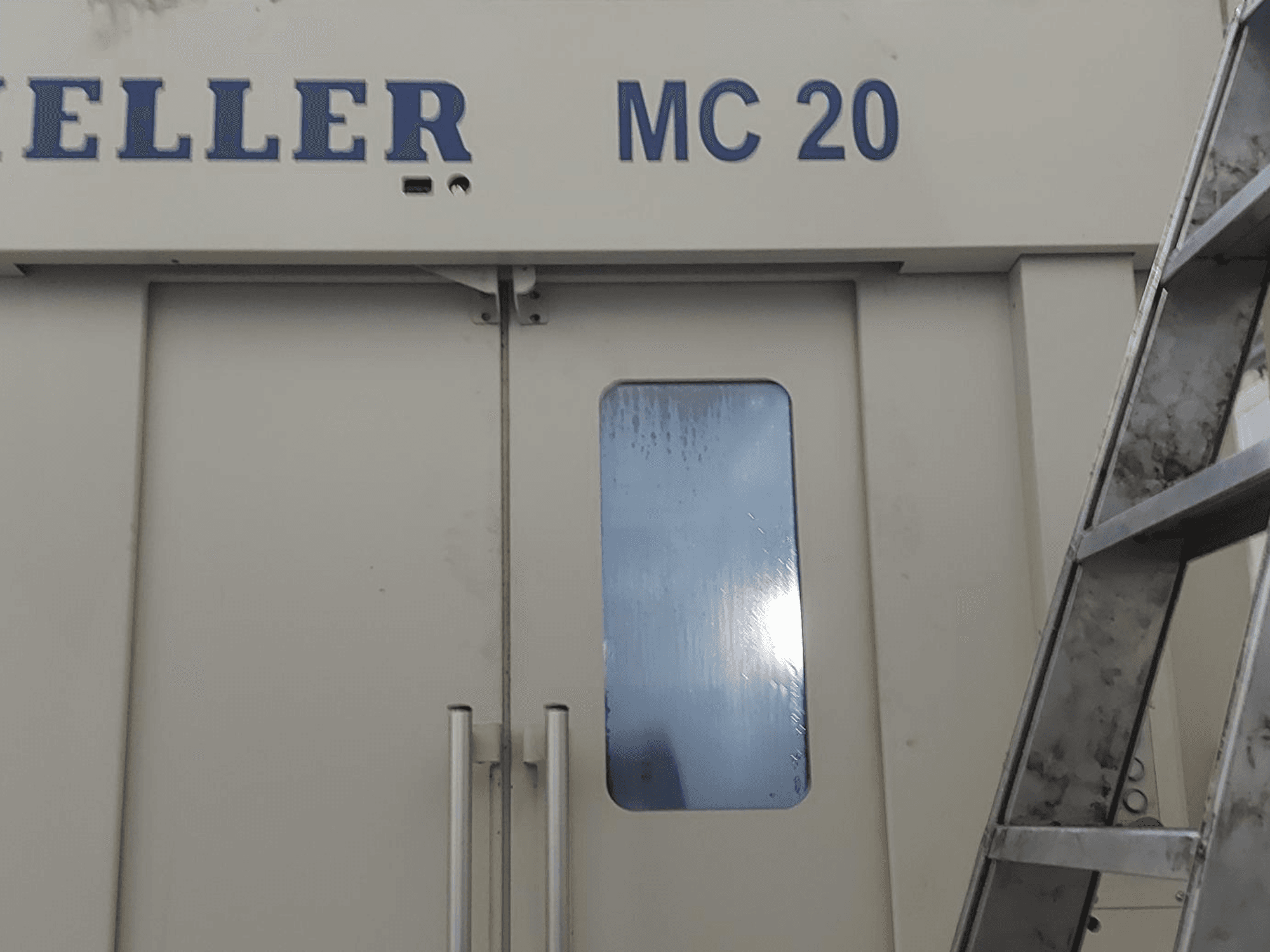 HELLER MC 20 horisontaaltöötluskeskuse esiplaanil, millel on näha uksekäepidemed ja väike aken. Küljel redel.