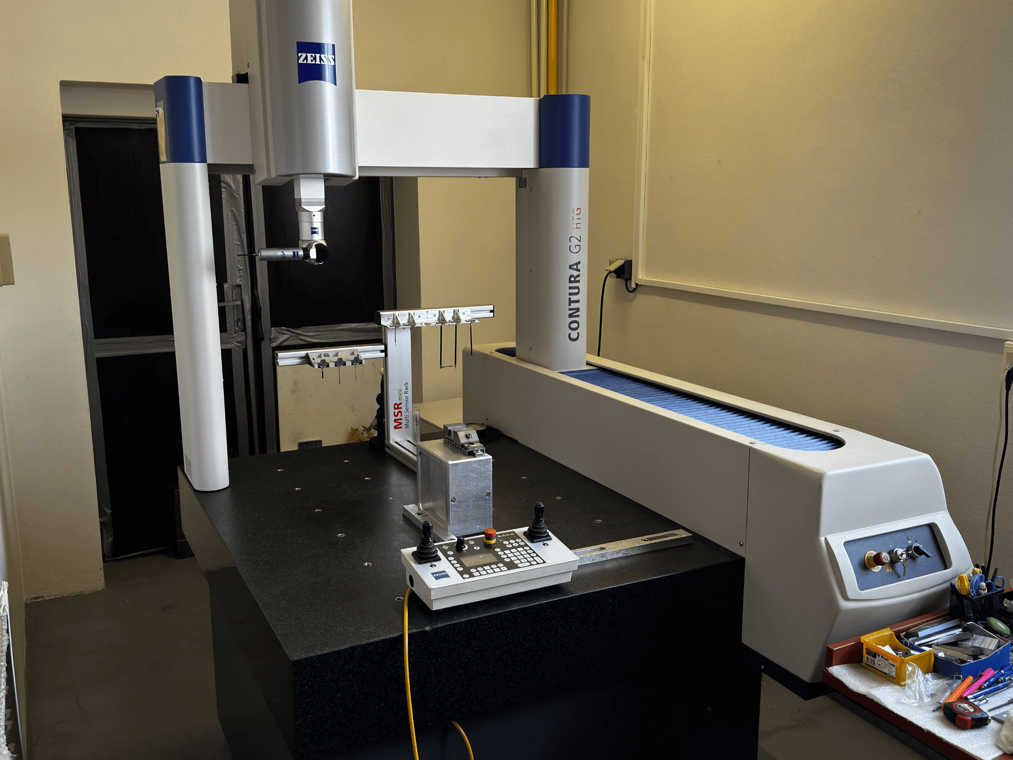 ZEISS Contura G2 CMM laboris, esiplaanil mõõtmisvarre, juhtpaneeli ja kõrvalolevat tööruumi.