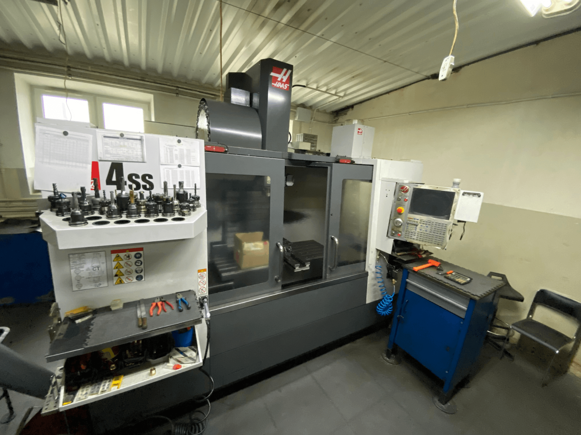 Haas VF-4SS vertikaalne töötlemiskeskus, vaade eest, millel on näha tööriistahoidikud ja juhtpaneel. Pildil on näha kasutatavad tööriistad ja töötsoon.