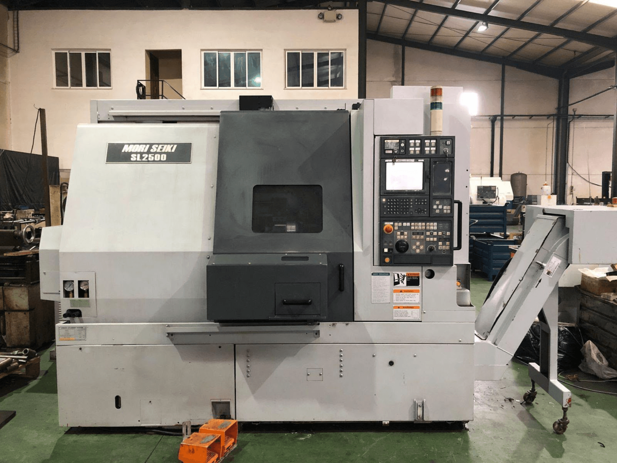DMG Mori Seiki SL 2500 Y treimis- ja freesikeskus, külgvaade, millel on näha juhtpaneel ja laastutranspordilint.