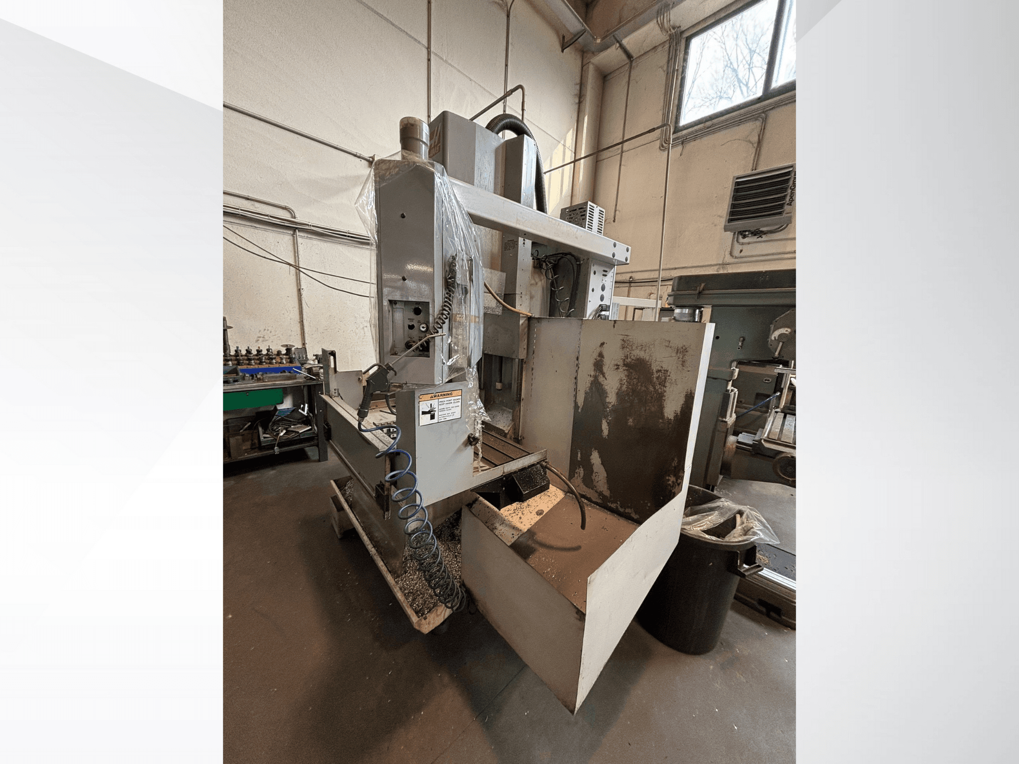 Vertikaalne freespink koos kaitsekattega, külgvaade; sisaldab jahutusvedeliku voolikut ja juhtpaneeli, mis on nähtav. Ideaalne töötlemiseks.