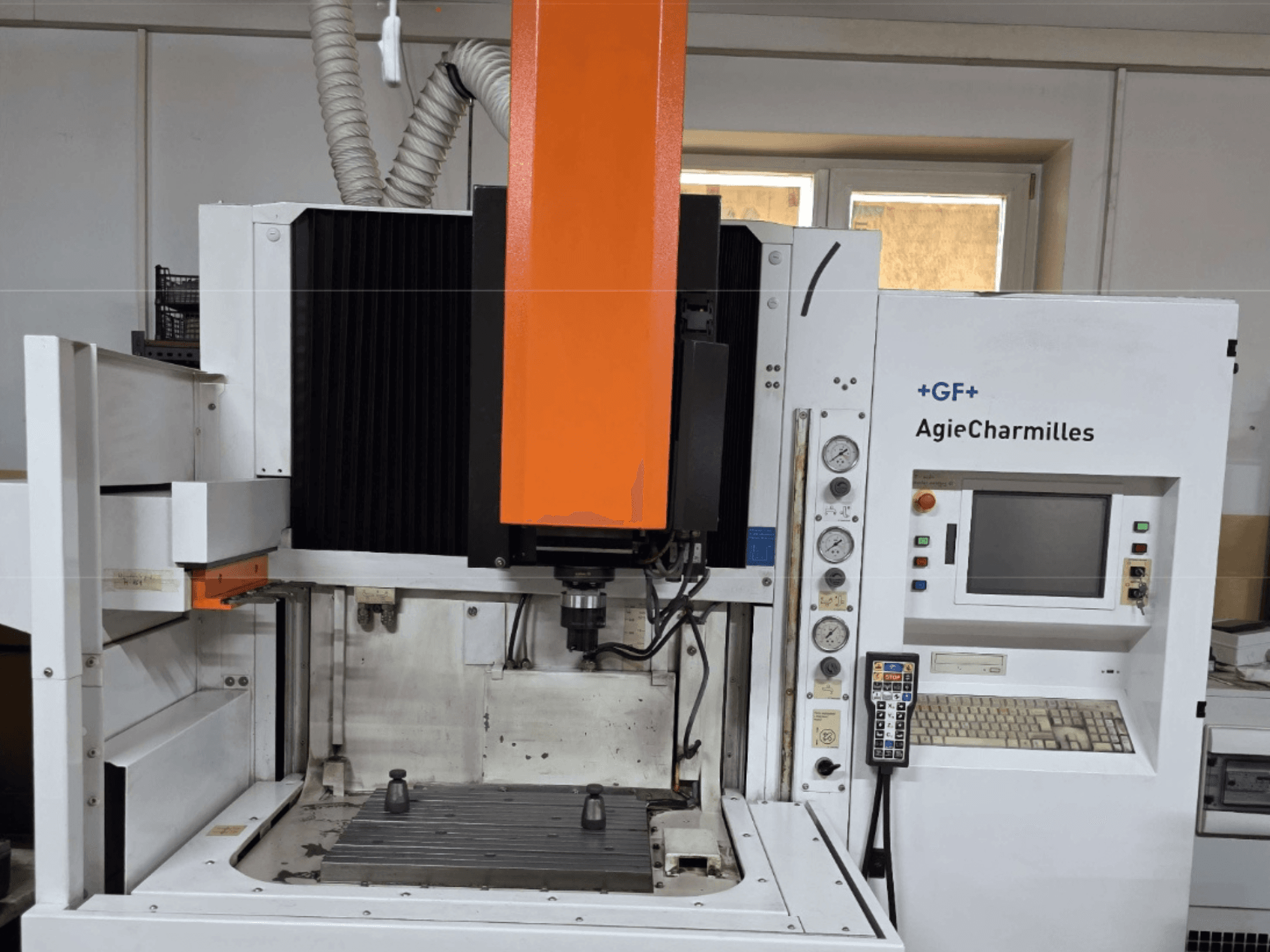 AgieCharmilles töötluskeskus esivaates suure oranži spindli, juhtpaneeli ja nähtava töölauaga.