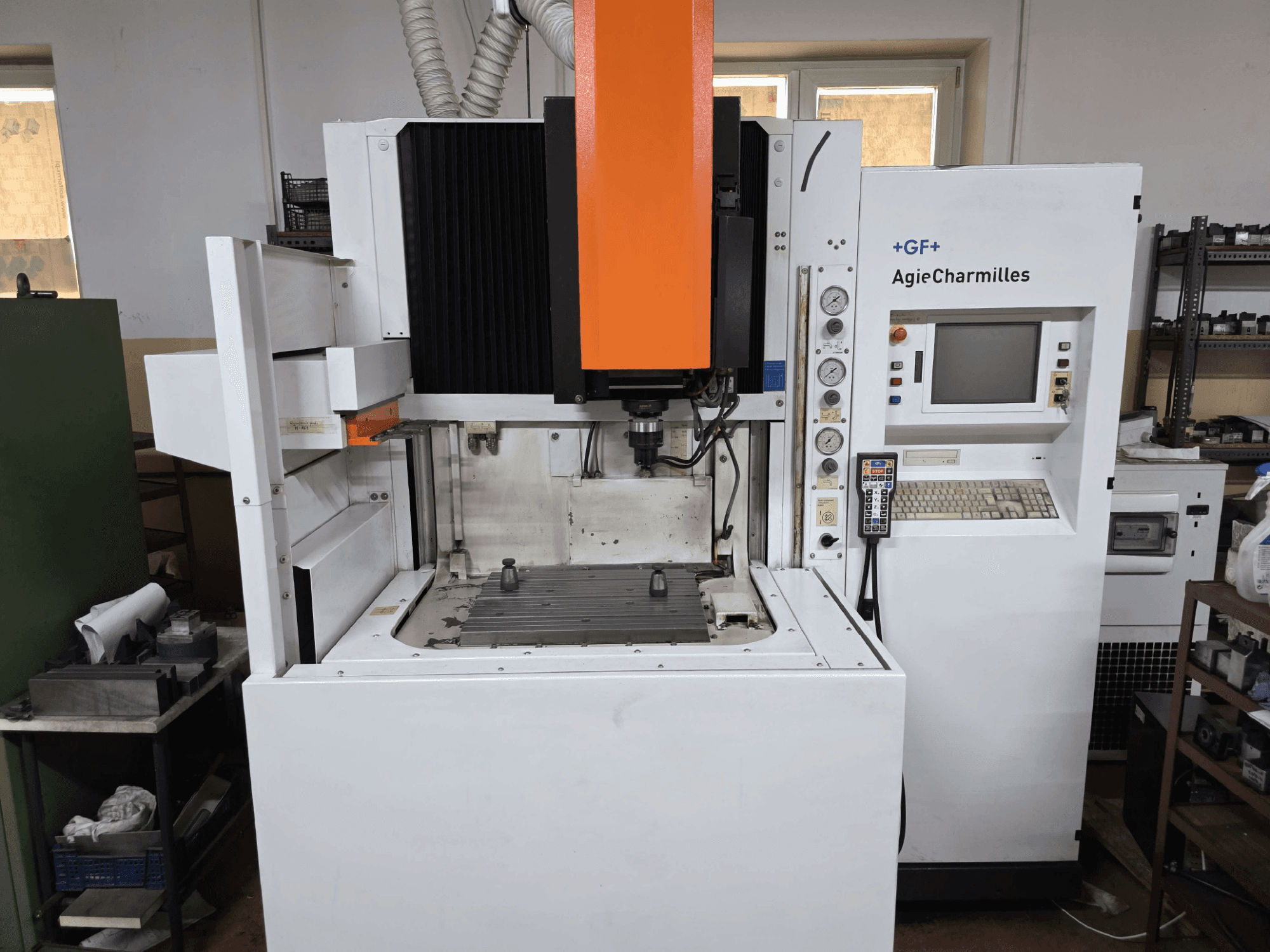 GF AgieCharmilles CNC-tööpink, esivaade silmatorkava oranži spindli, digitaalse juhtpaneeli ja paigaldatud puurilauaga.