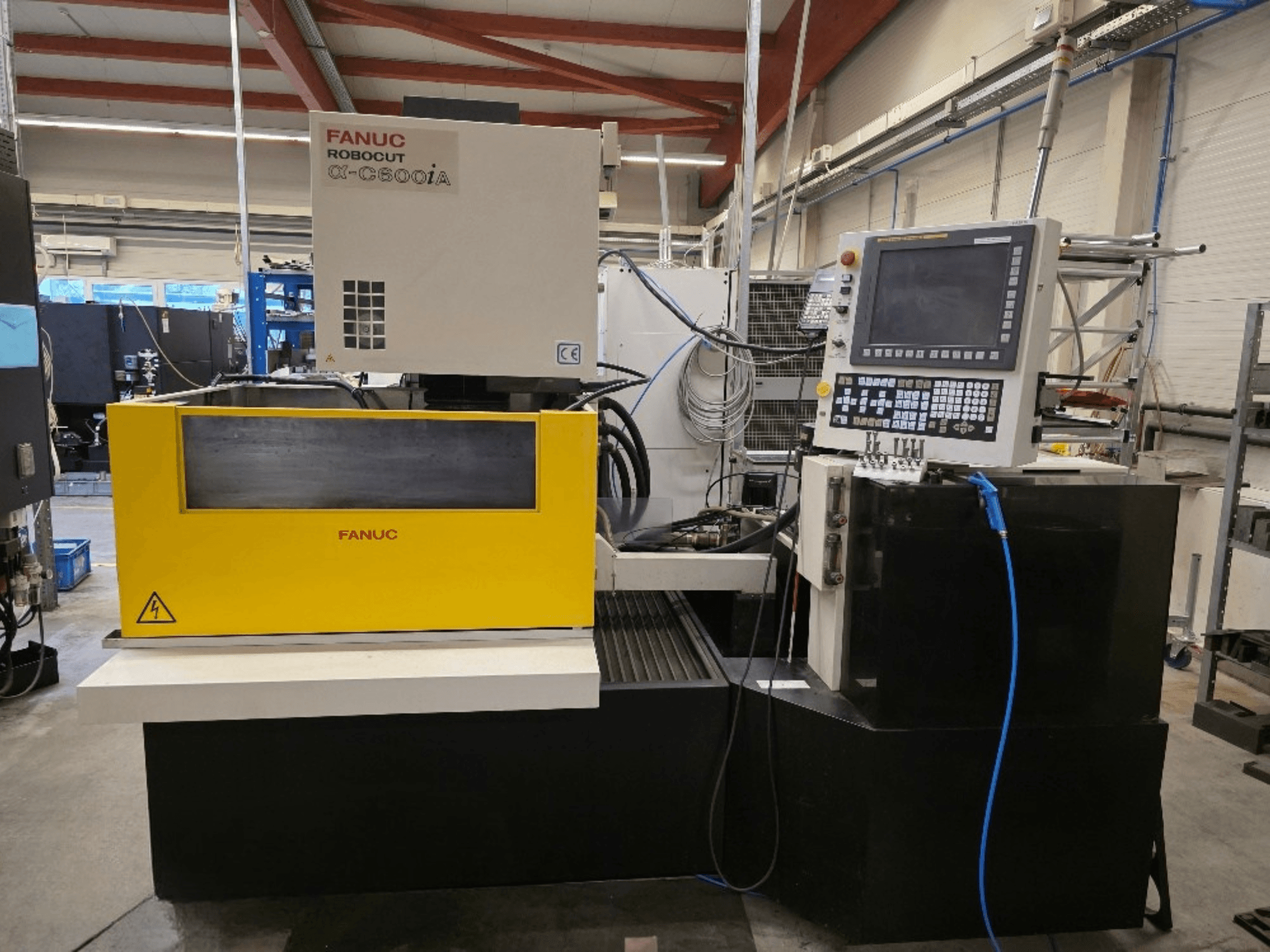 FANUC Robocut α-C600iA traadilõikepink eesvaates, millel on kollane juhtpaneel ja digitaalne ekraan.