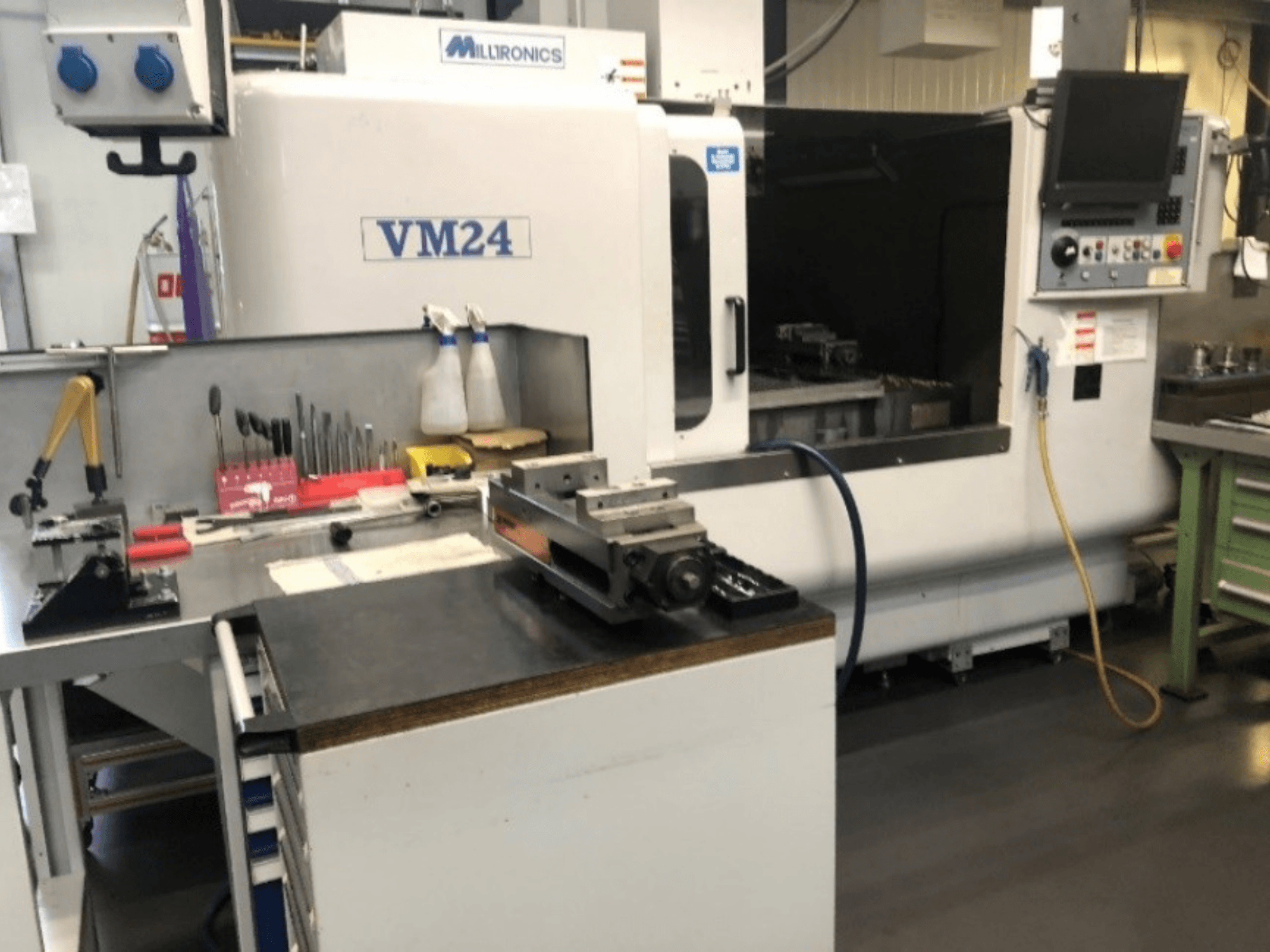 Milltronics VM24 CNC-pingi tööruum. Eesvaade tööriistade ja seadmetega töölaual.