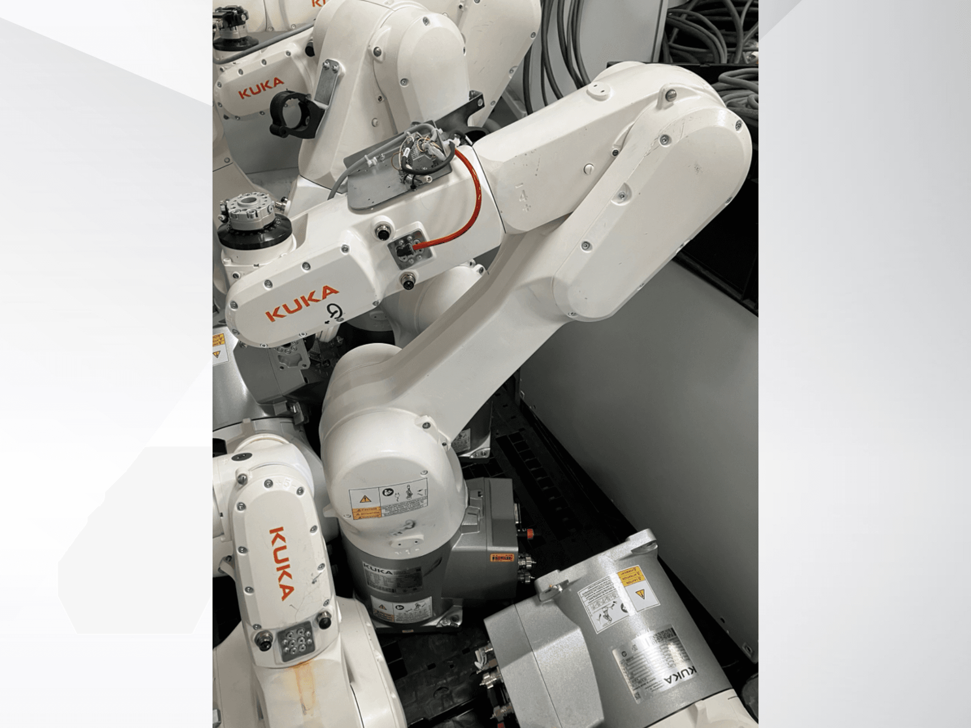 KUKA KR 6 R900 CR robotkäsi, külgvaade; nähtavad mootorid ja pistikud, märgistatud ohutushoiatused ja mehaanilised käed.