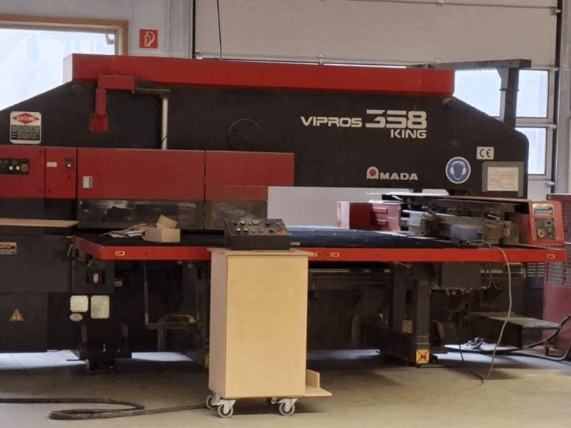 CNC-stantspress AMADA VIPROS 358 KING külgvaates, millel on juhtpaneel ja tööriistade hoiuruum.