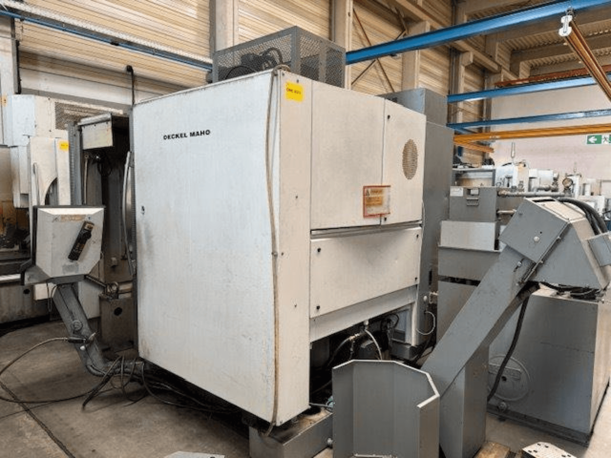 DECKEL MAHO DMC 100 V vertikaalne töötlemiskeskus, külgvaade, kus on näha juhtpaneel ja erinevad lisaseadmed.