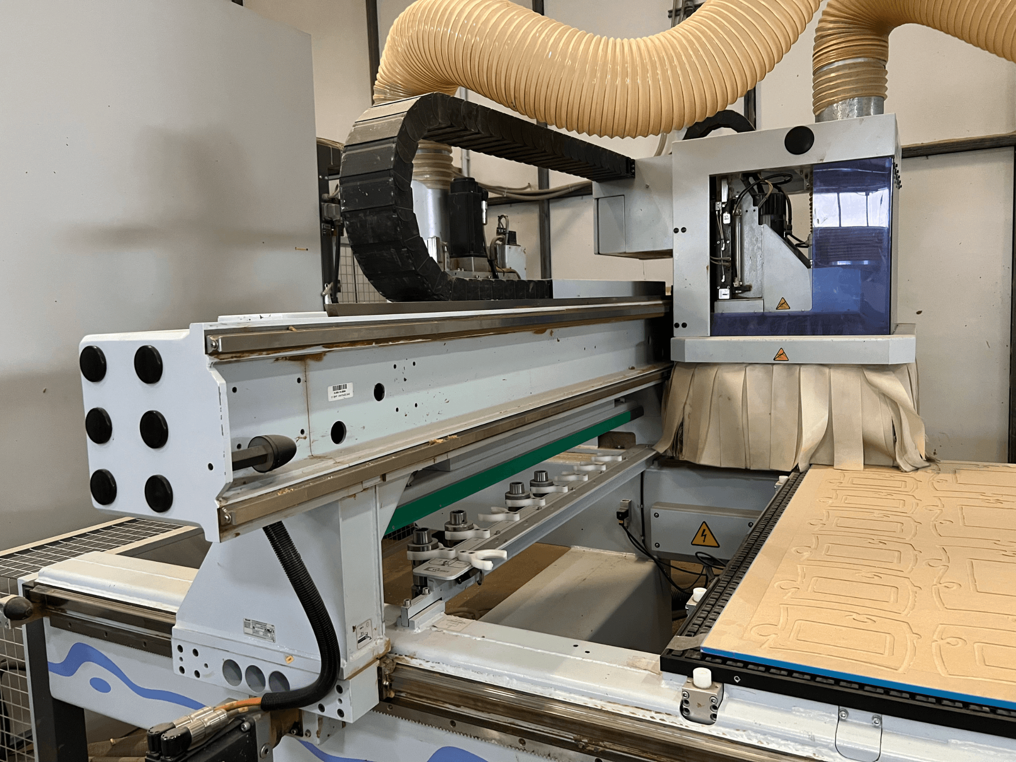 Külgvaade sinise ja hõbedase juhtpaneeliga CNC-juurest, mis on varustatud tolmueemalduse ja puidulõikeplaadiga.