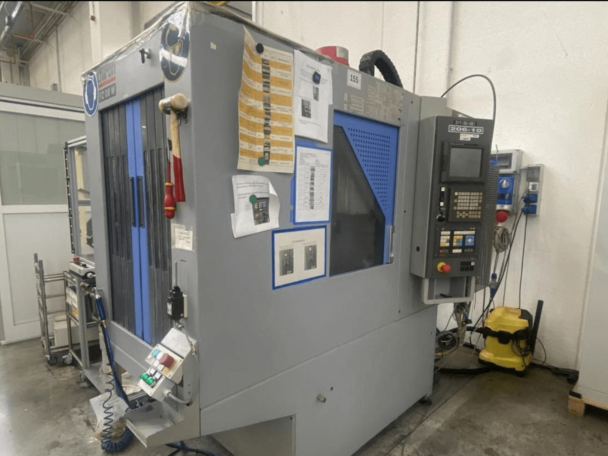 Shin Lini CNC-masin, esiplaanil, millel on juhtpaneel, juhtnupud ja ohutusjuhendid.