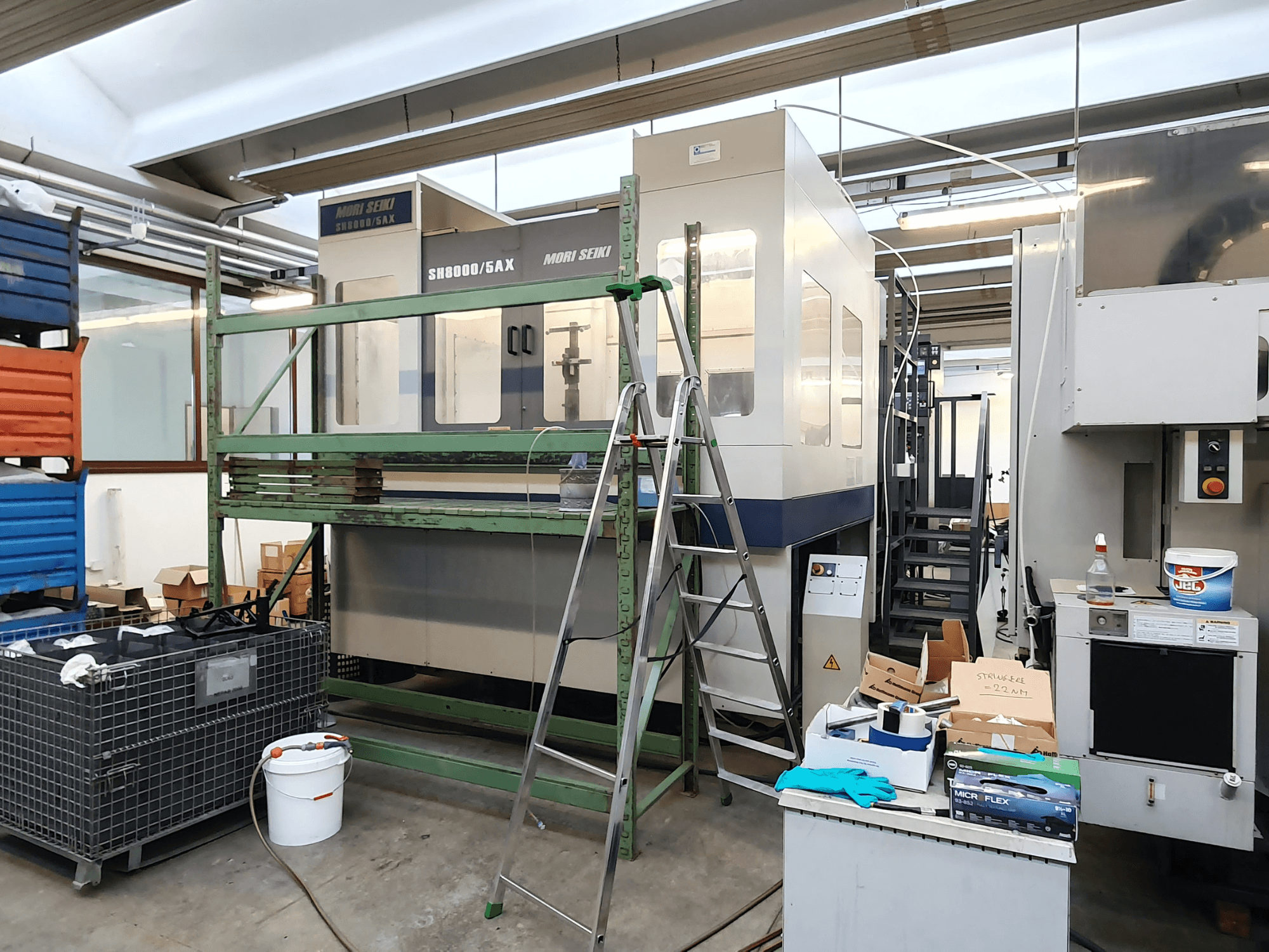 Mori Seiki SH-8000/5AX CNC-tööpink töökojas, esiplaanil, töökoja tööriistad ja hoiukastid lähedal.