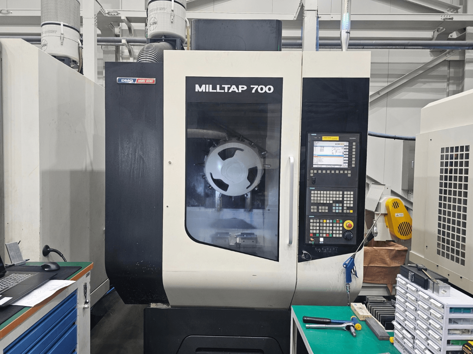 DMG MORI MILLTAP 700 vertikaalne töötlemiskeskus, vaade eest, millel on näha juhtpaneel, spindel ja töötsooni üksikasjad.