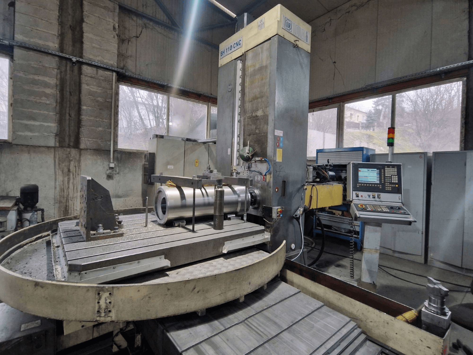 LOLA BH 110 CNC-puurimispink töökojas, esiplaanil, metalltükiga ja juhtpaneeliga.