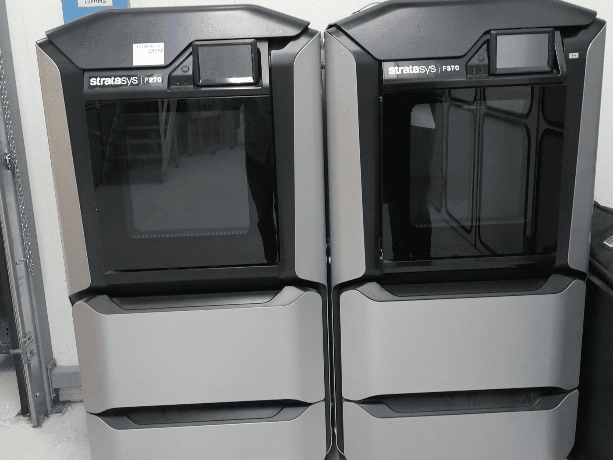 Stratasys F370 topeltplastist 3D-printerid esiplaanil, millel on elegantse musta ja hõbedase disainiga juhtimisekraanid.